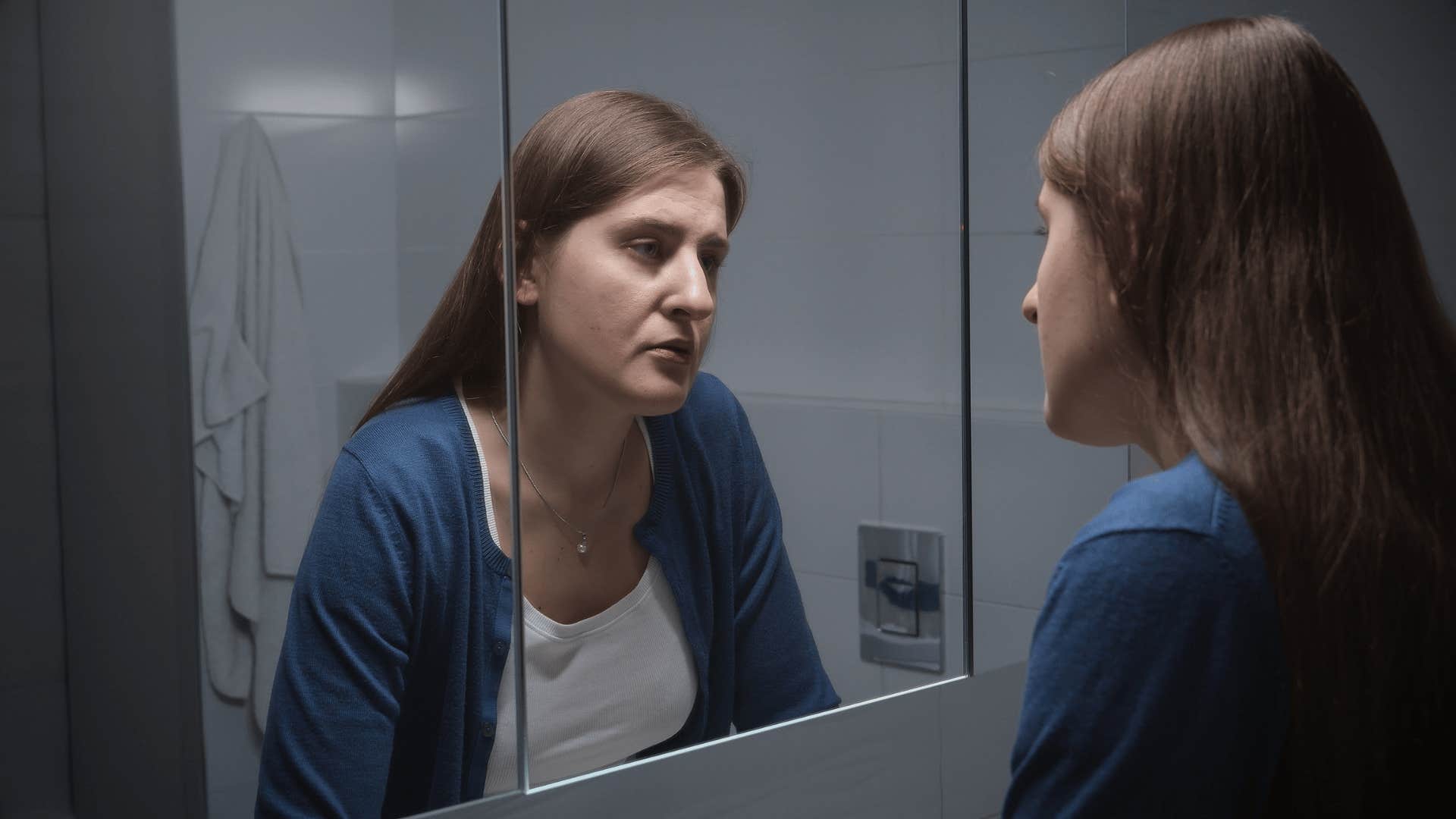 upset woman looking in mirror