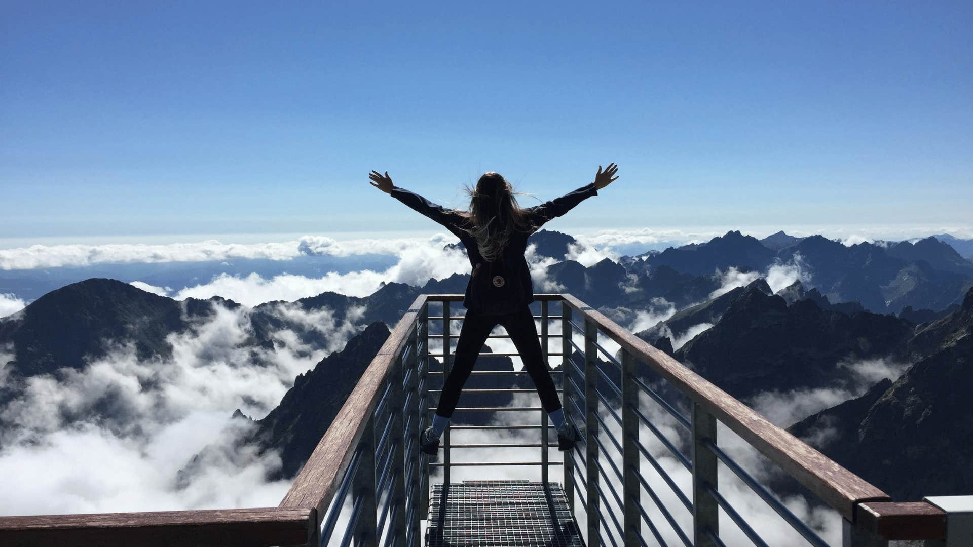 woman standing on railing over mountain