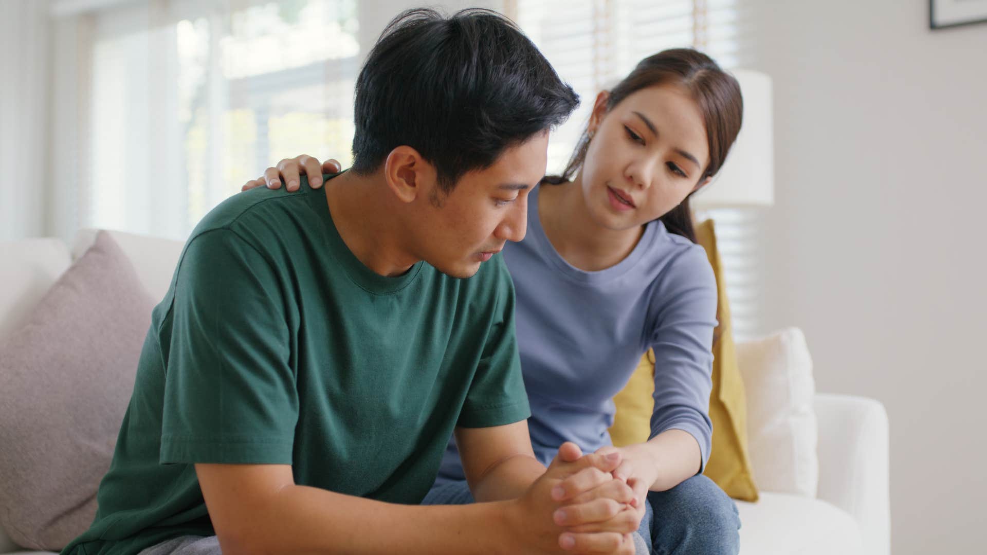 Woman comforting her upset partner on the couch.