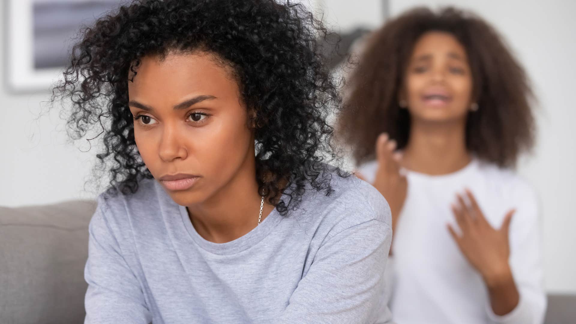 Upset woman turned away from her sister arguing with her. 