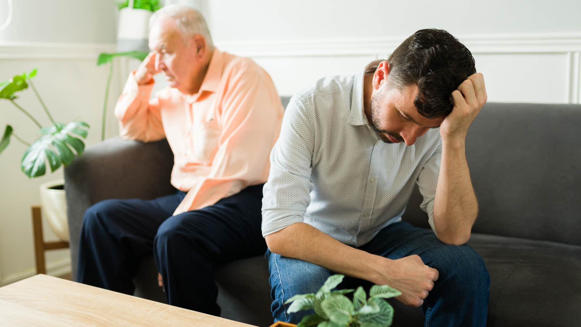 Adult son looking upset sitting in front of his dad.