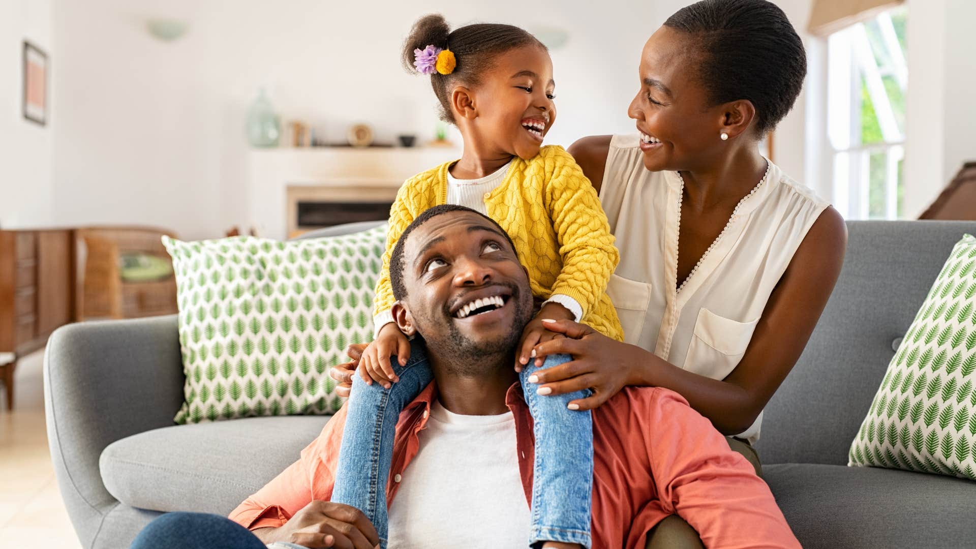 Young family laughing and smiling in their living room.