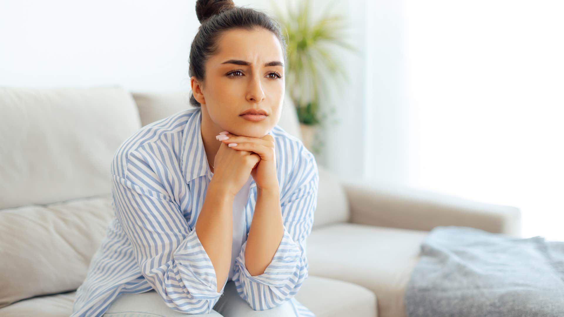 Young woman looking upset sitting on a couch.