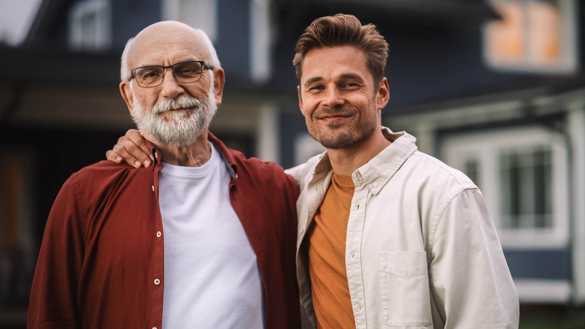 Adult son smiling and hugging his dad.