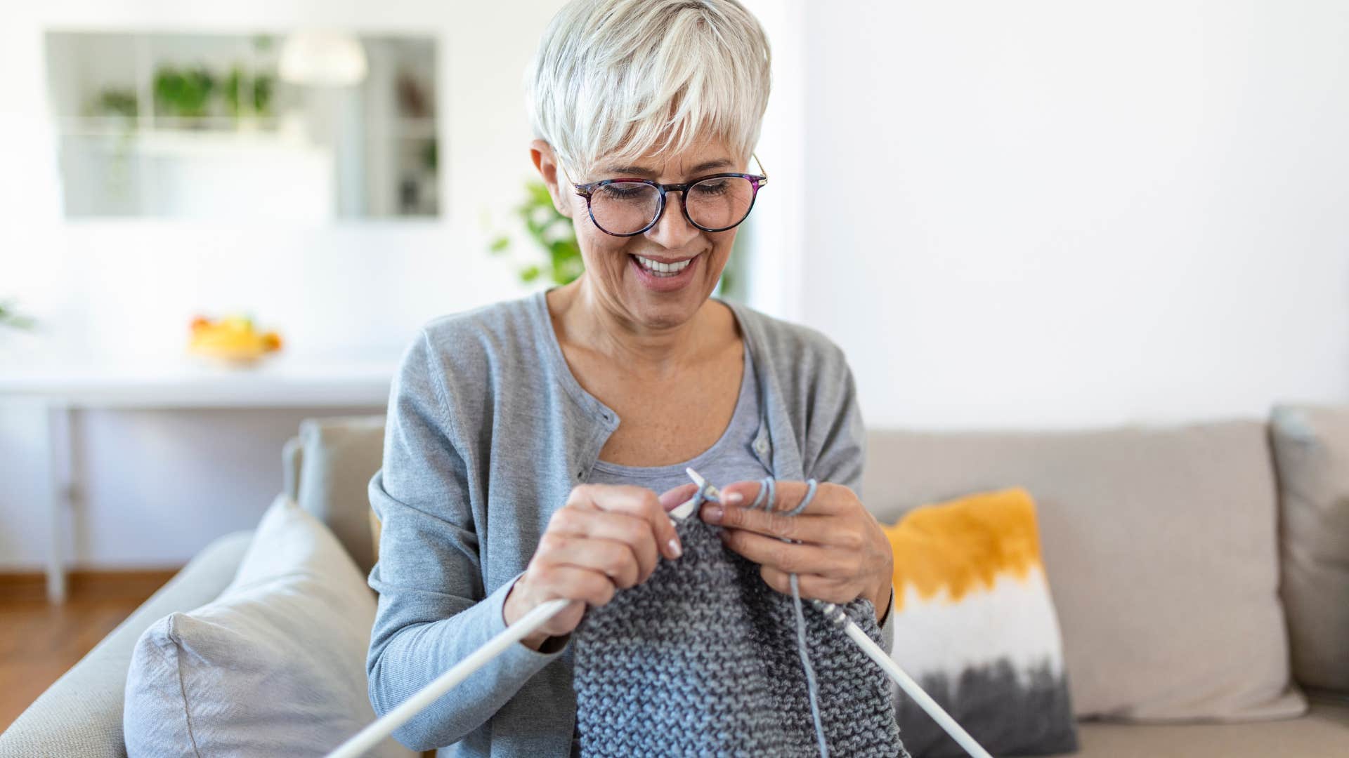 Older woman knitting in her living room.