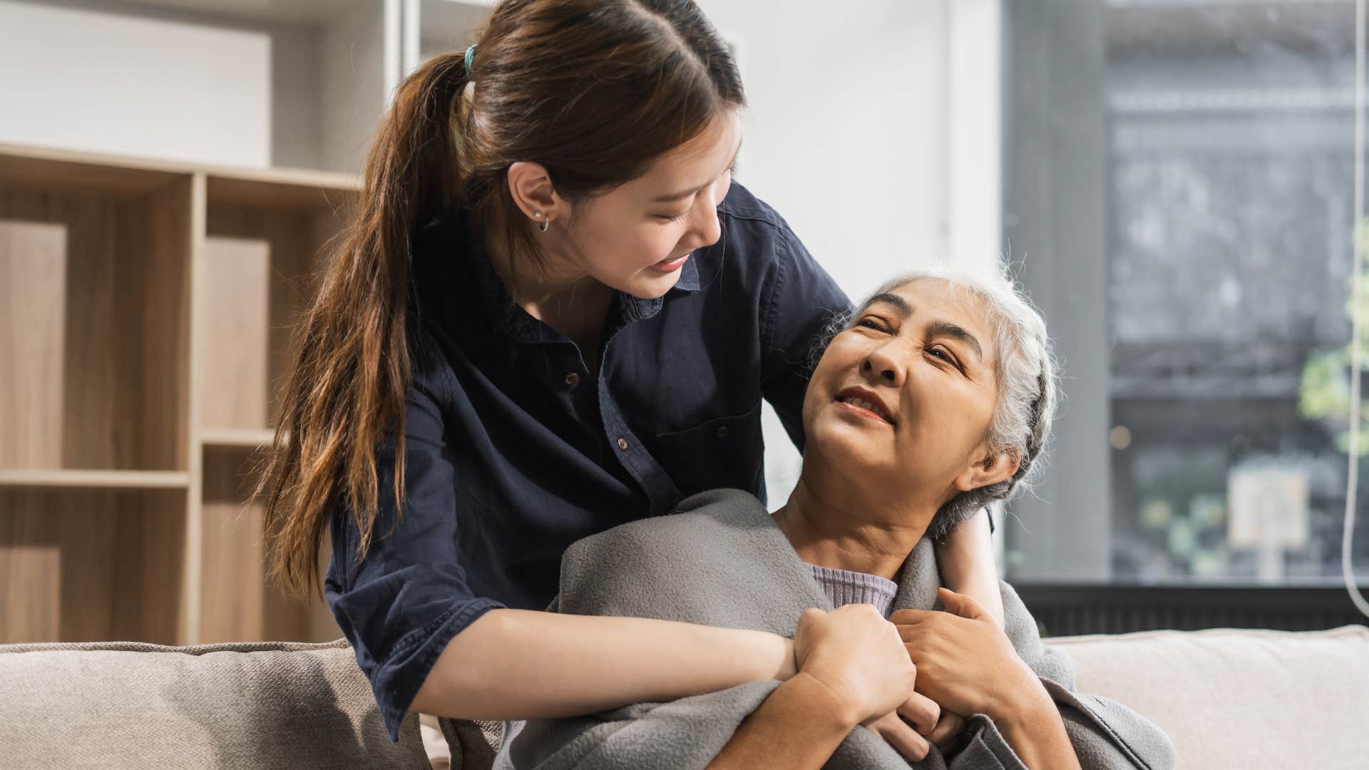 Woman hugging her older mom on the couch.