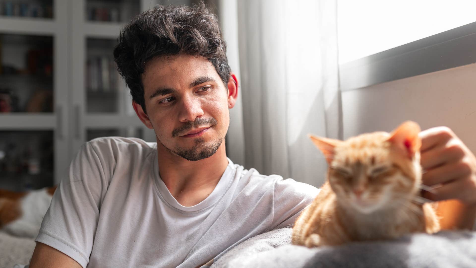 Man smiling while petting his cat on the couch.