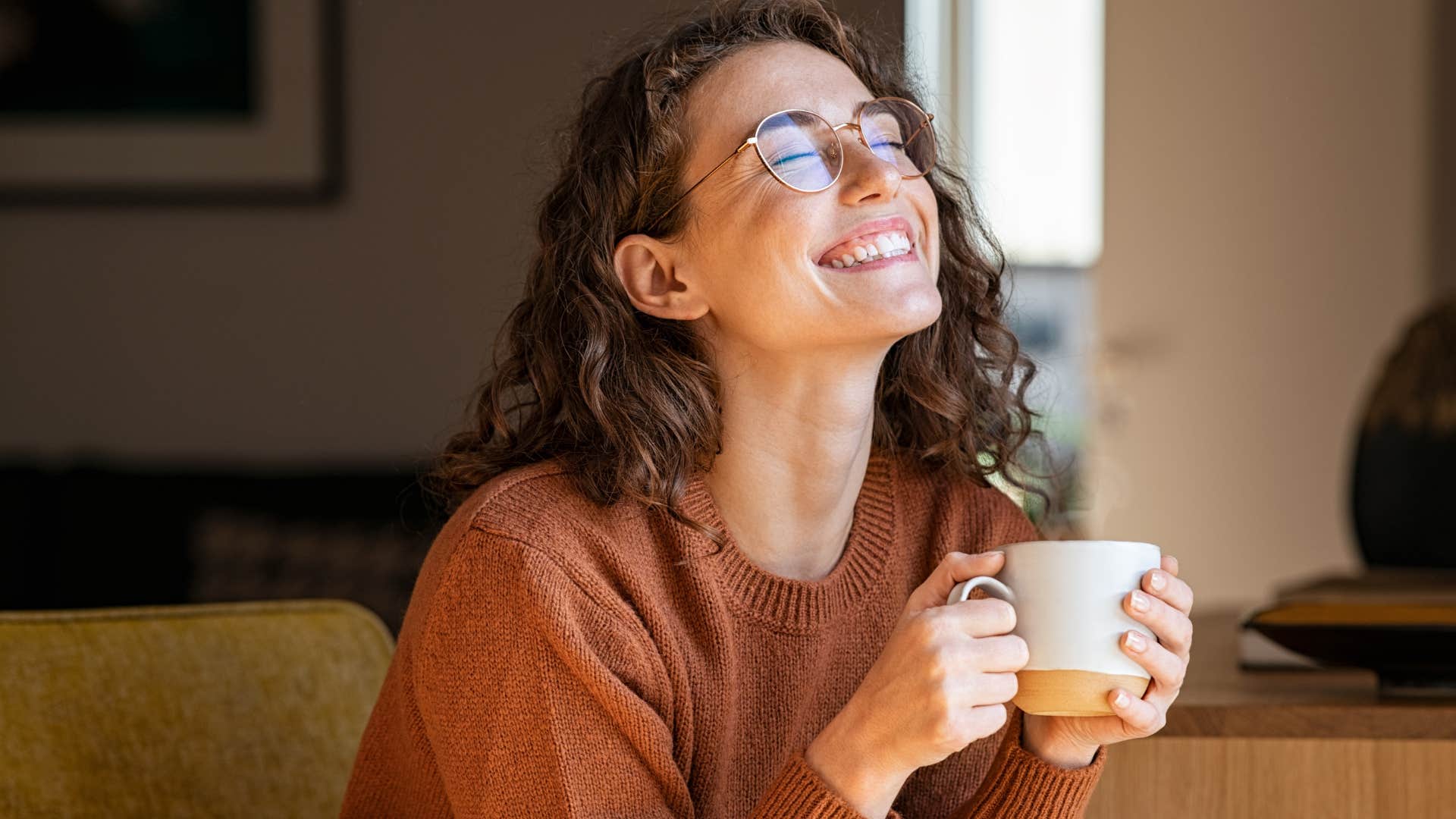 Woman smiling and holding a cup of coffee.