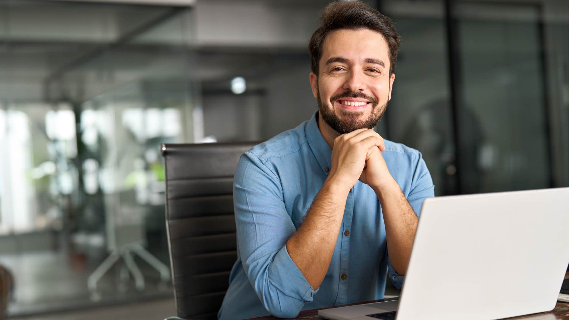 Man smiling in front of his laptop at work.