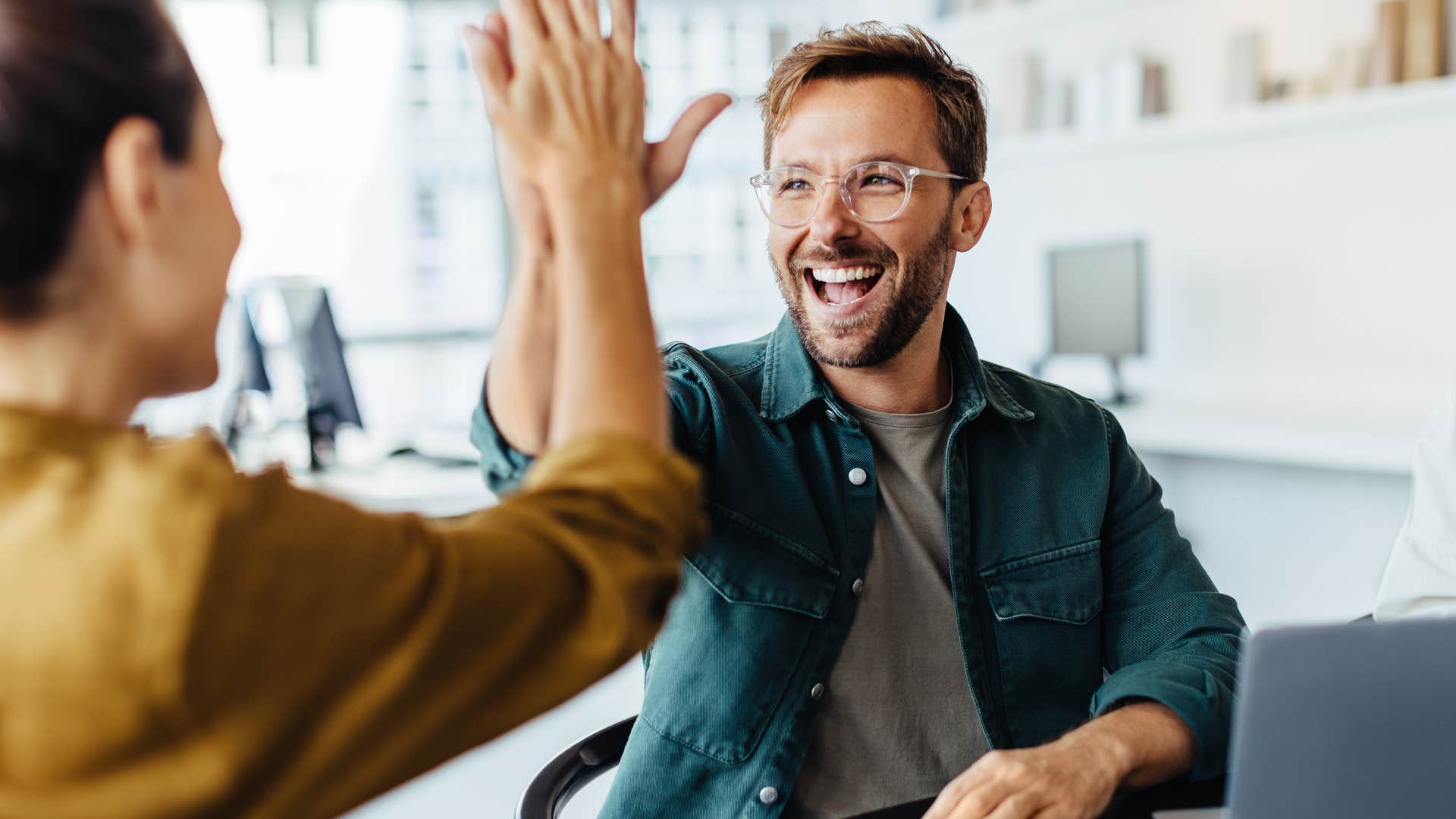 Man smiling and high-fiving a woman.