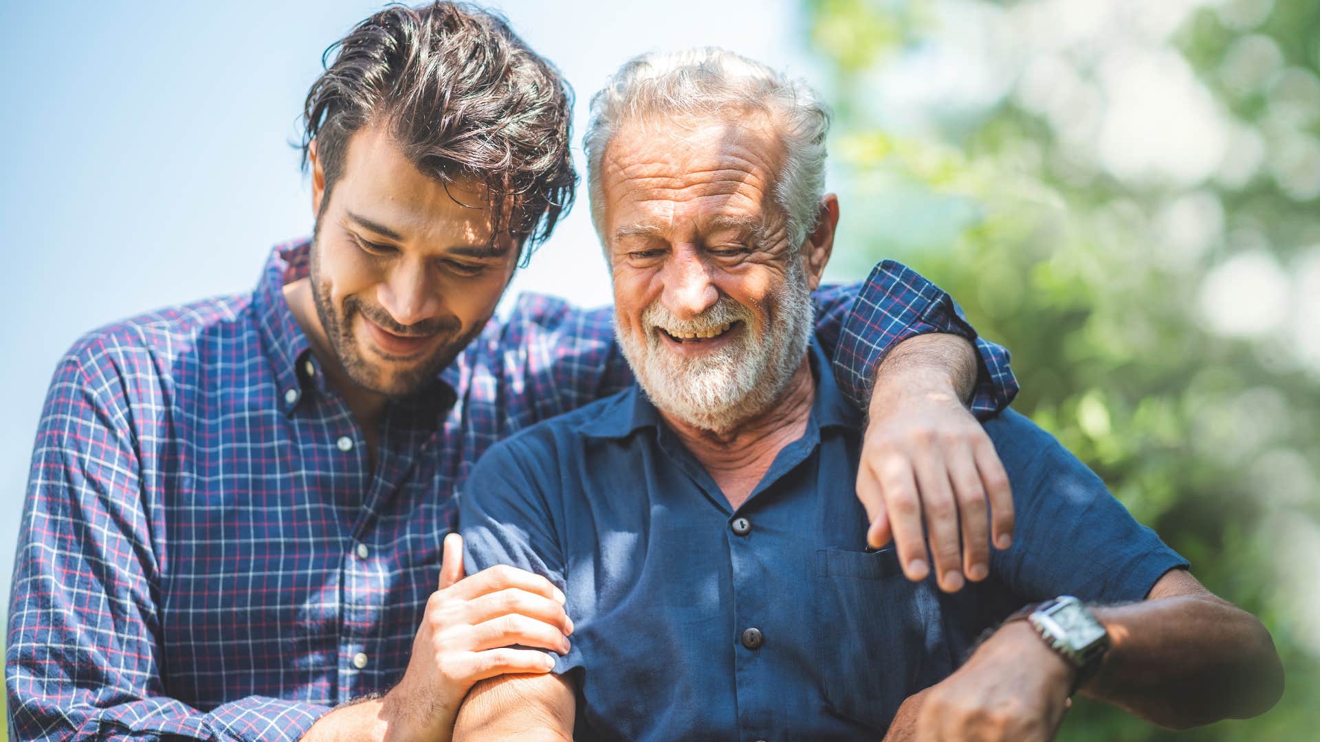 Adult son hugging his dad outside.