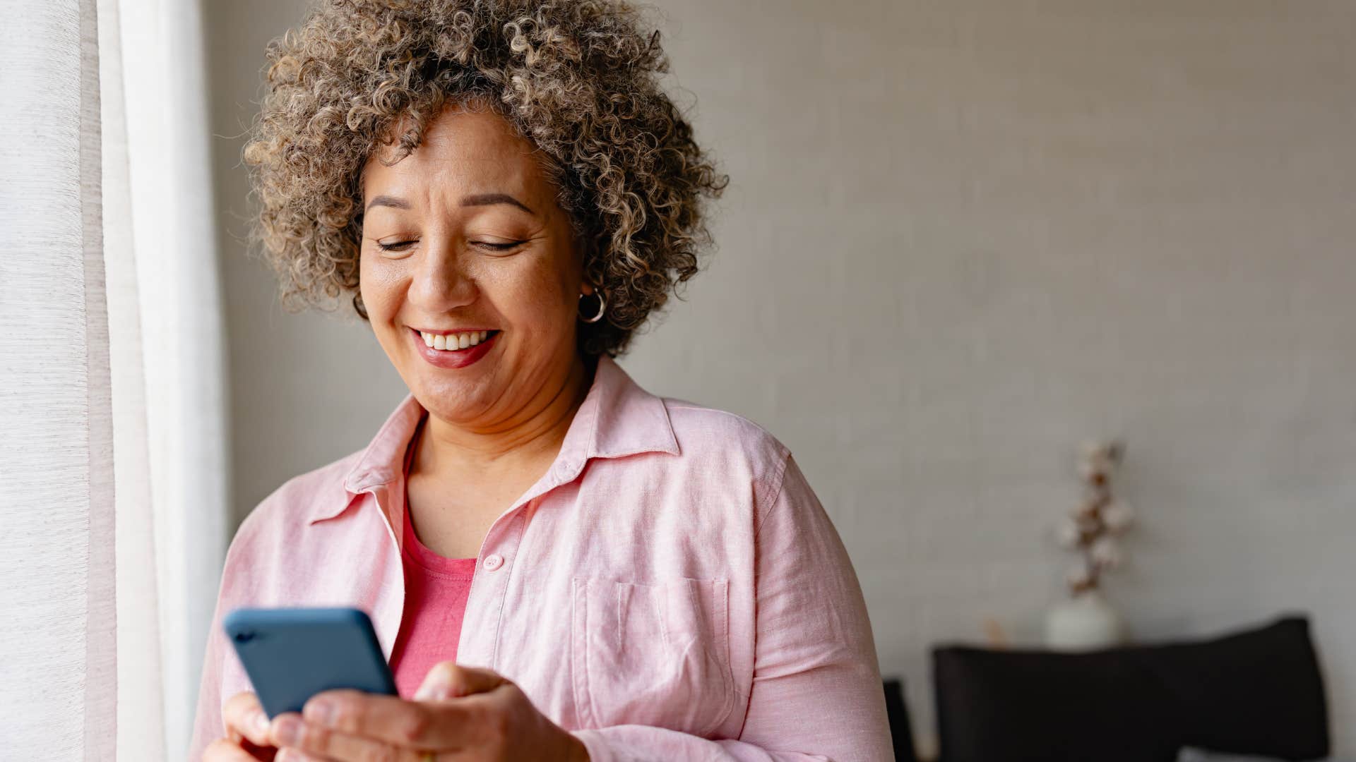 Woman smiling and texting on her phone.