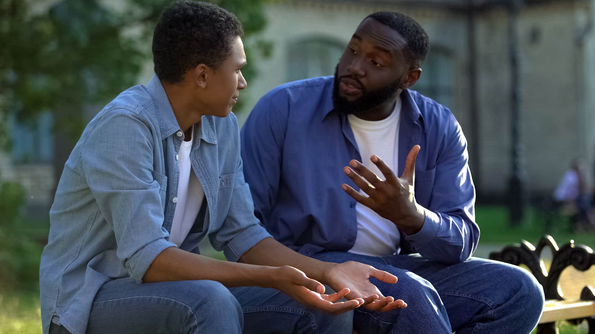 Father talking to his teenage son on a bench.