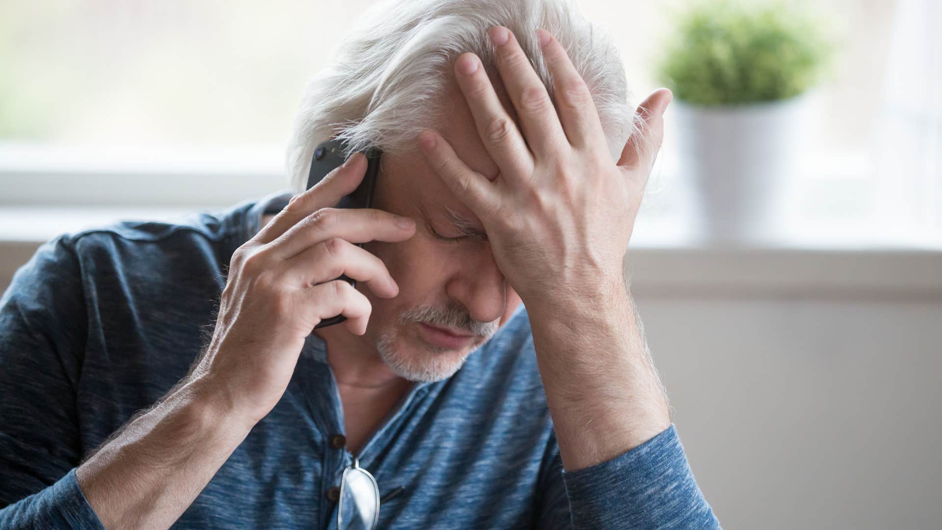 Older man looking sad talking on the phone.