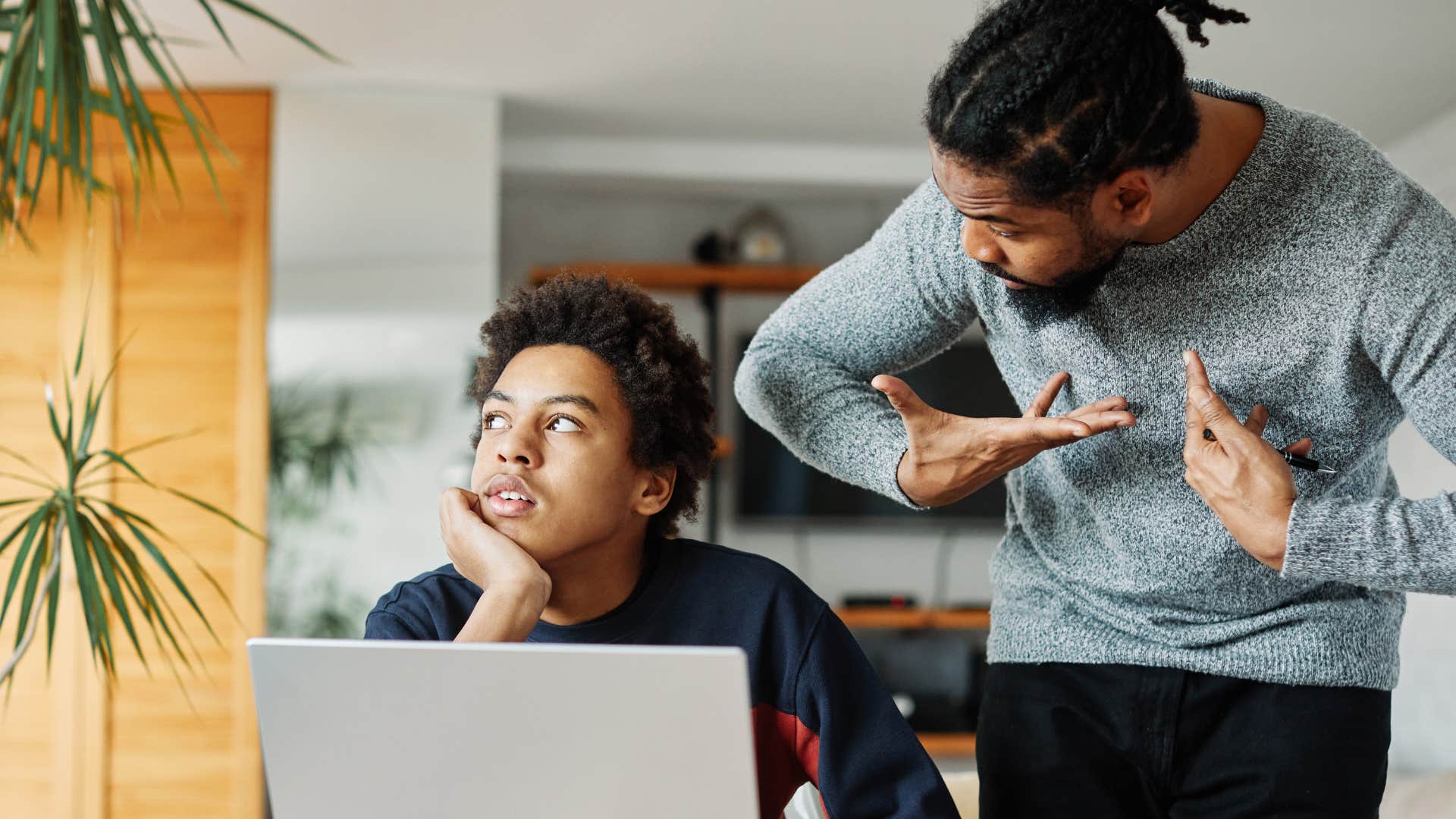 Young man looking annoyed while his dad yells at him