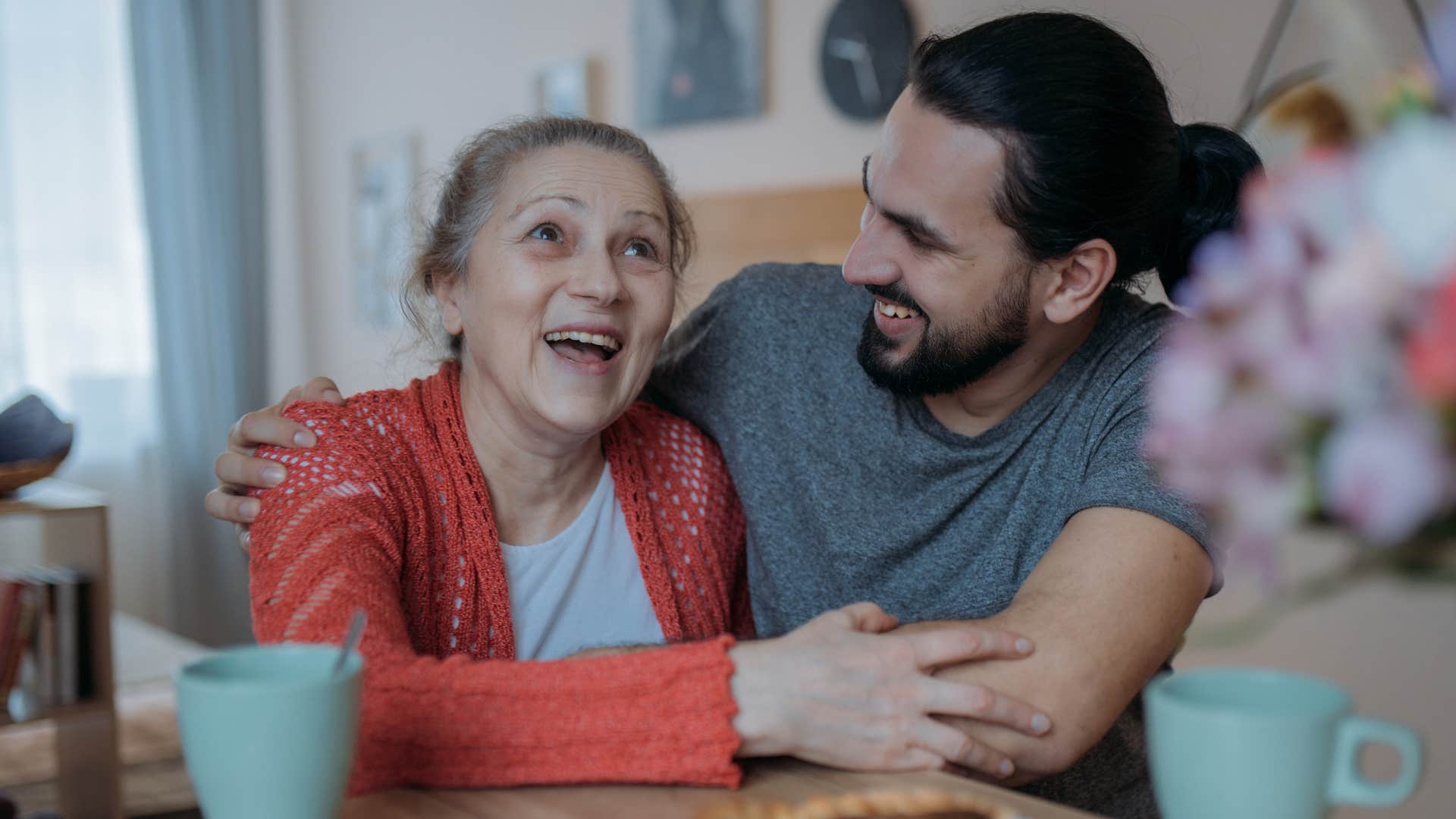 Woman smiling and hugging her adult son.