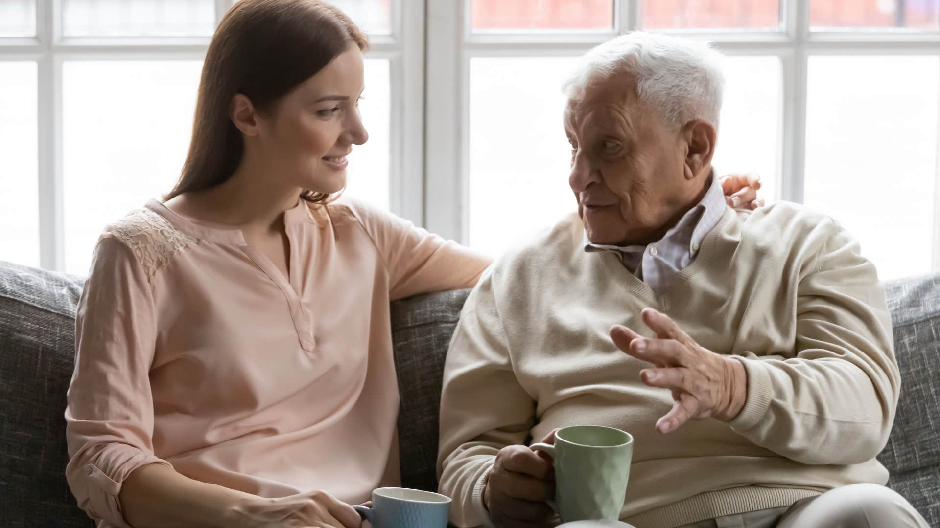 Older man talking to his smiling adult daughter.