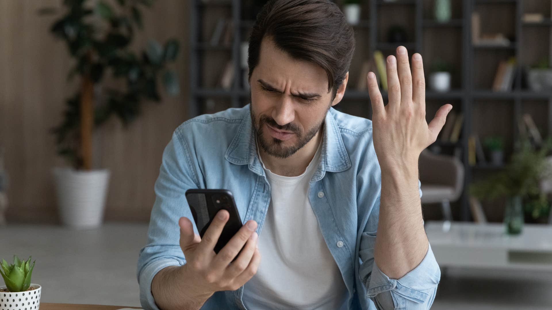 Man looking annoyed staring at his phone.