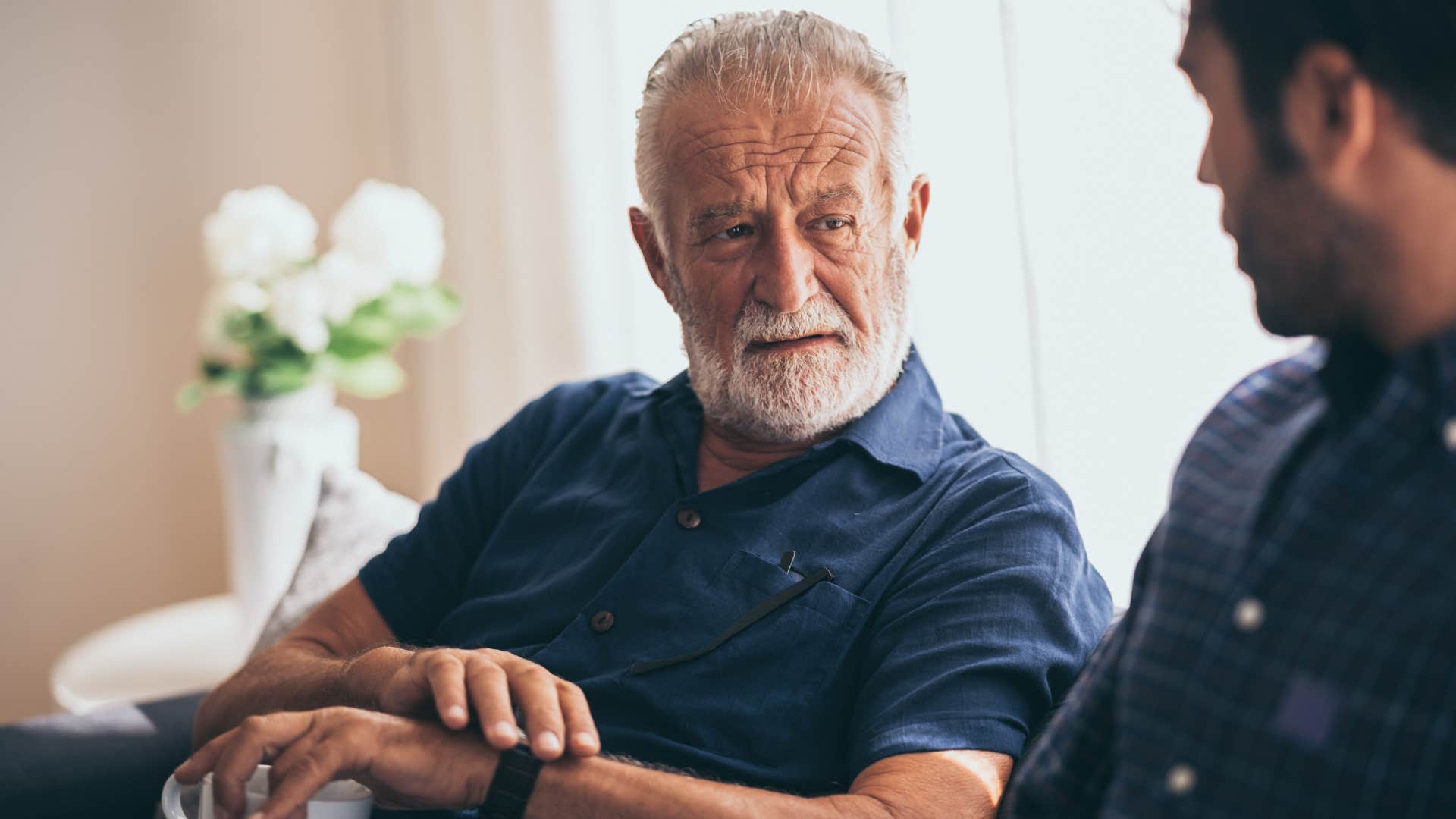 Older man looking annoyed talking to his son.