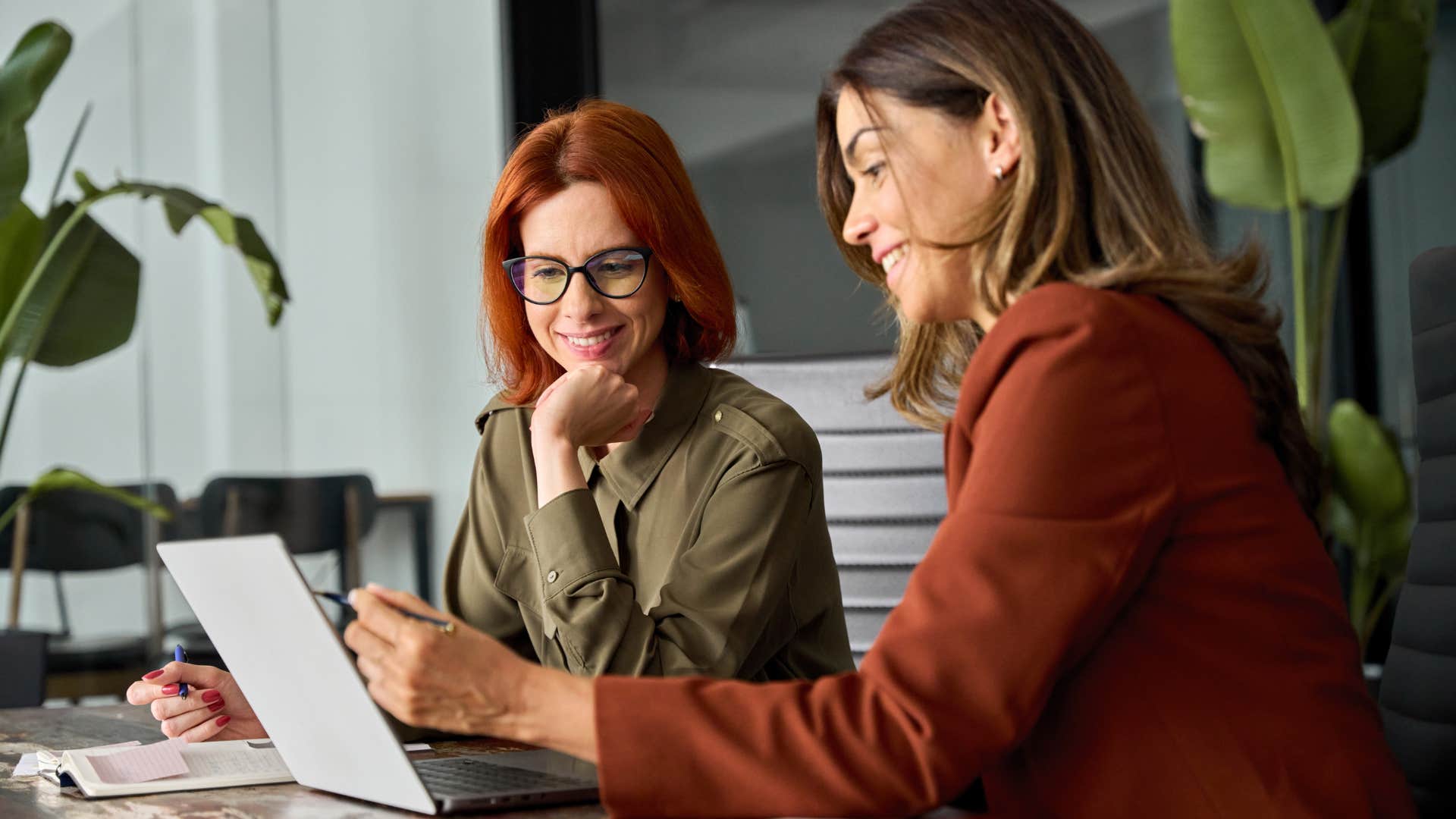 Two women working together on their laptops at work