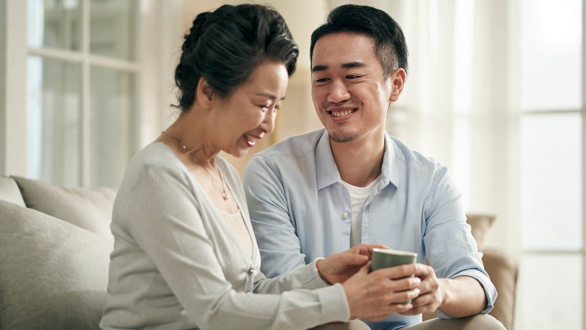 Son talking to his older mother on the couch