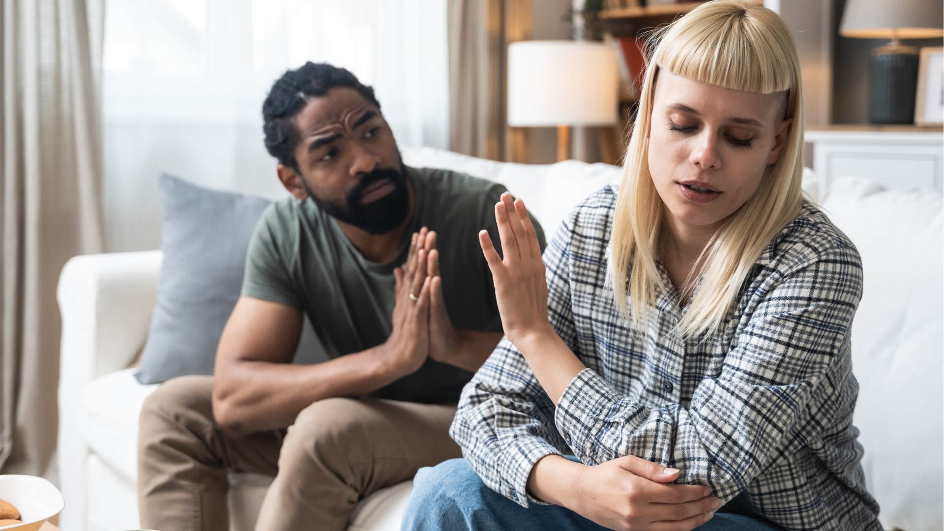 Couple arguing while sitting on their couch.