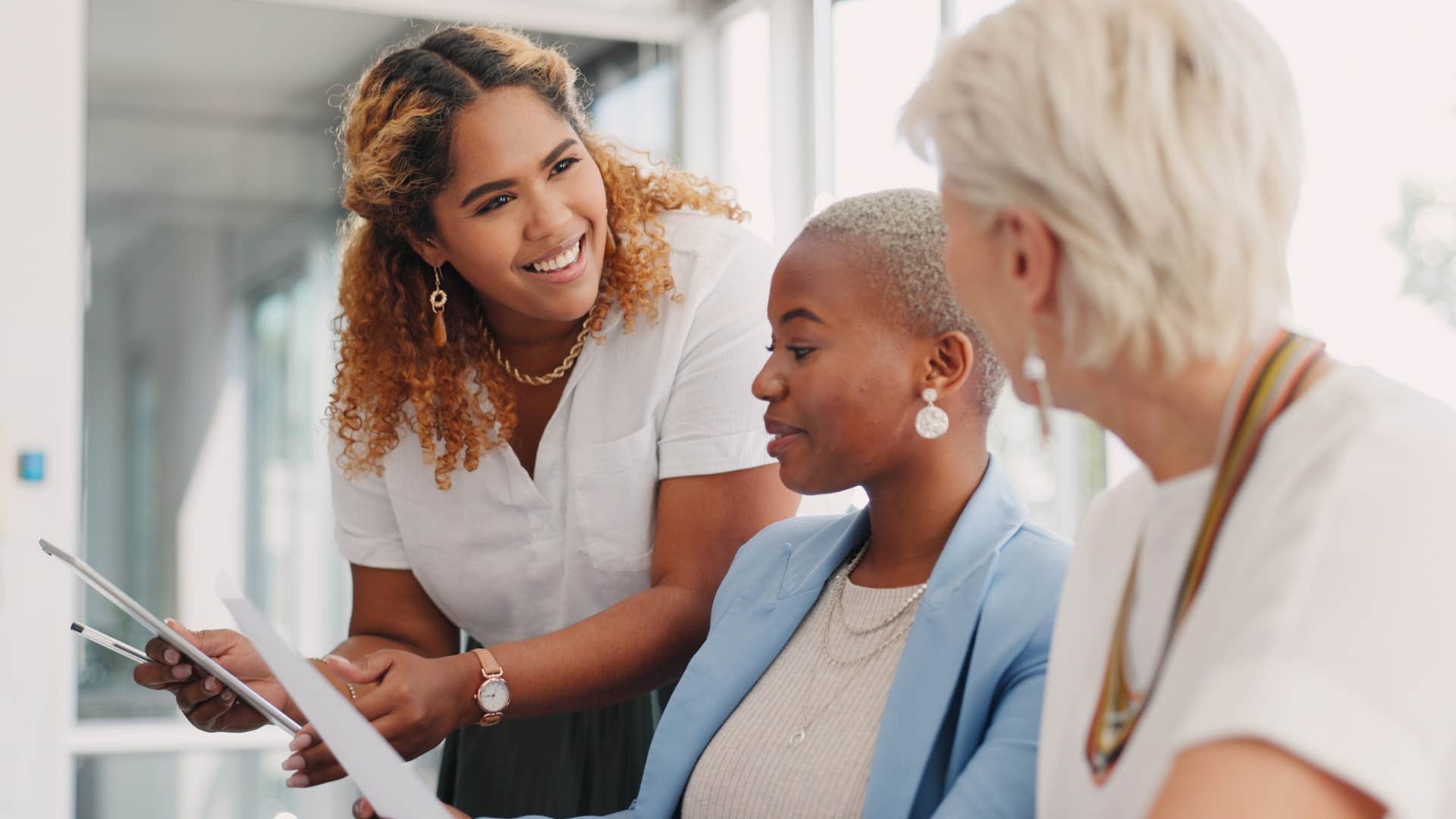 Woman talking to two peers at work and smiling