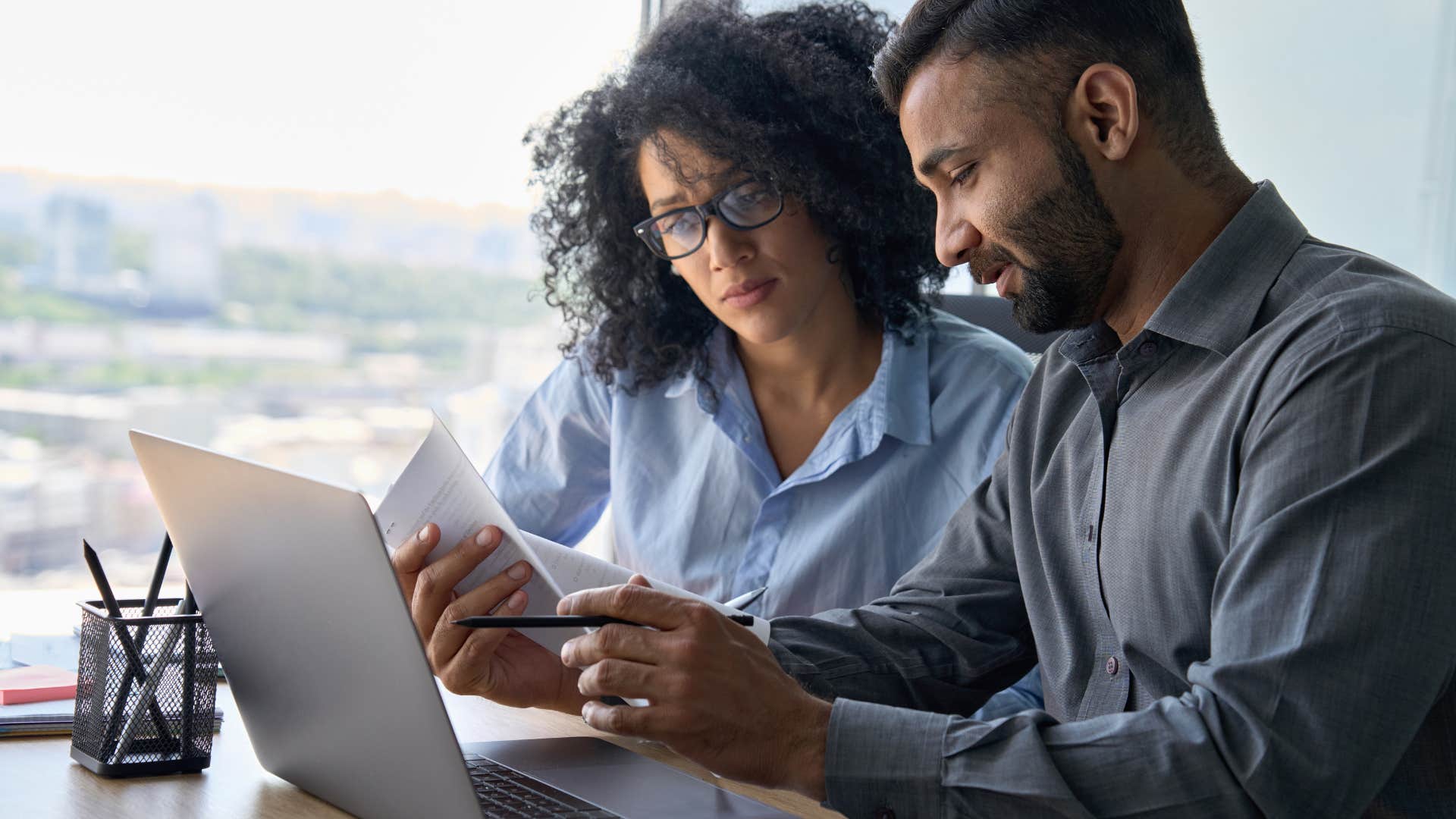 Co-workers talking and looking at a laptop together