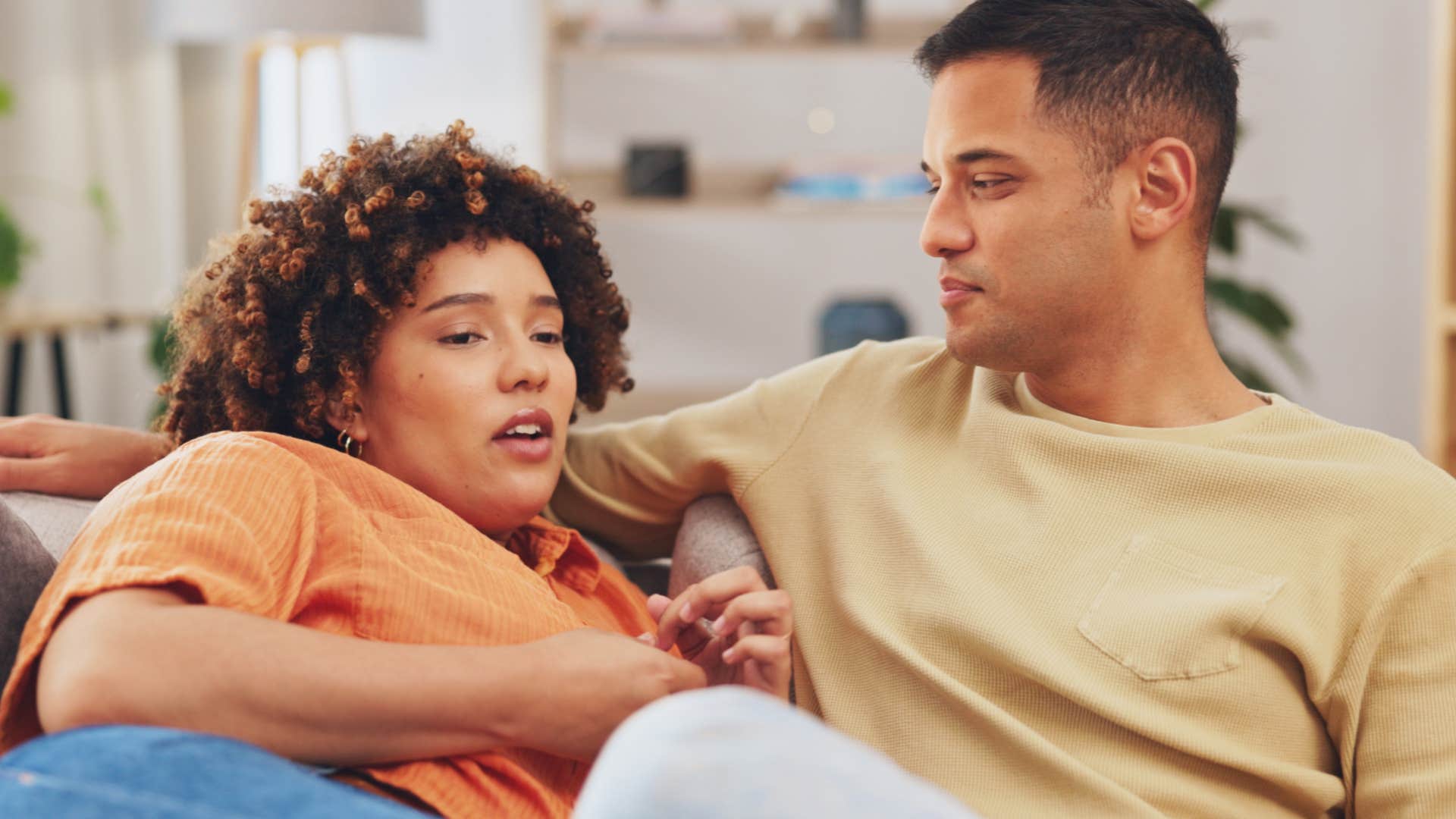 Couple smiling and talking to each other on the couch.