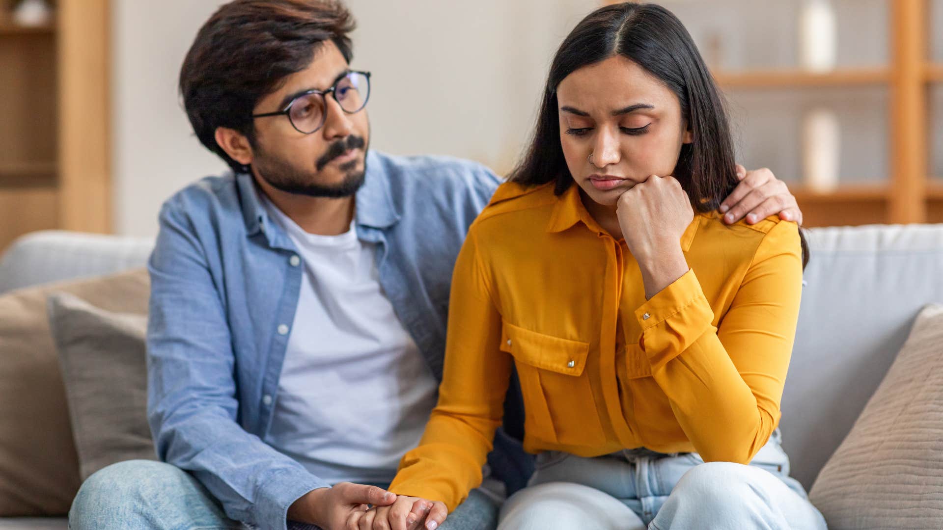 Man comforting his partner on the couch.