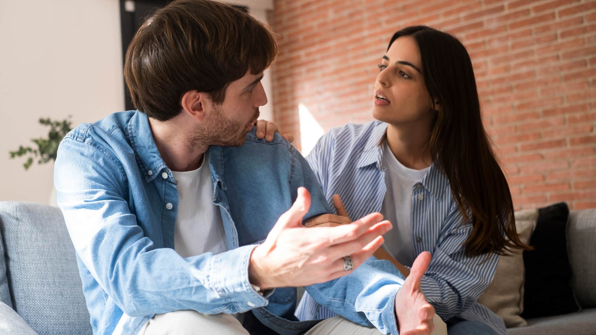 Man talking to his upset partner on the couch.