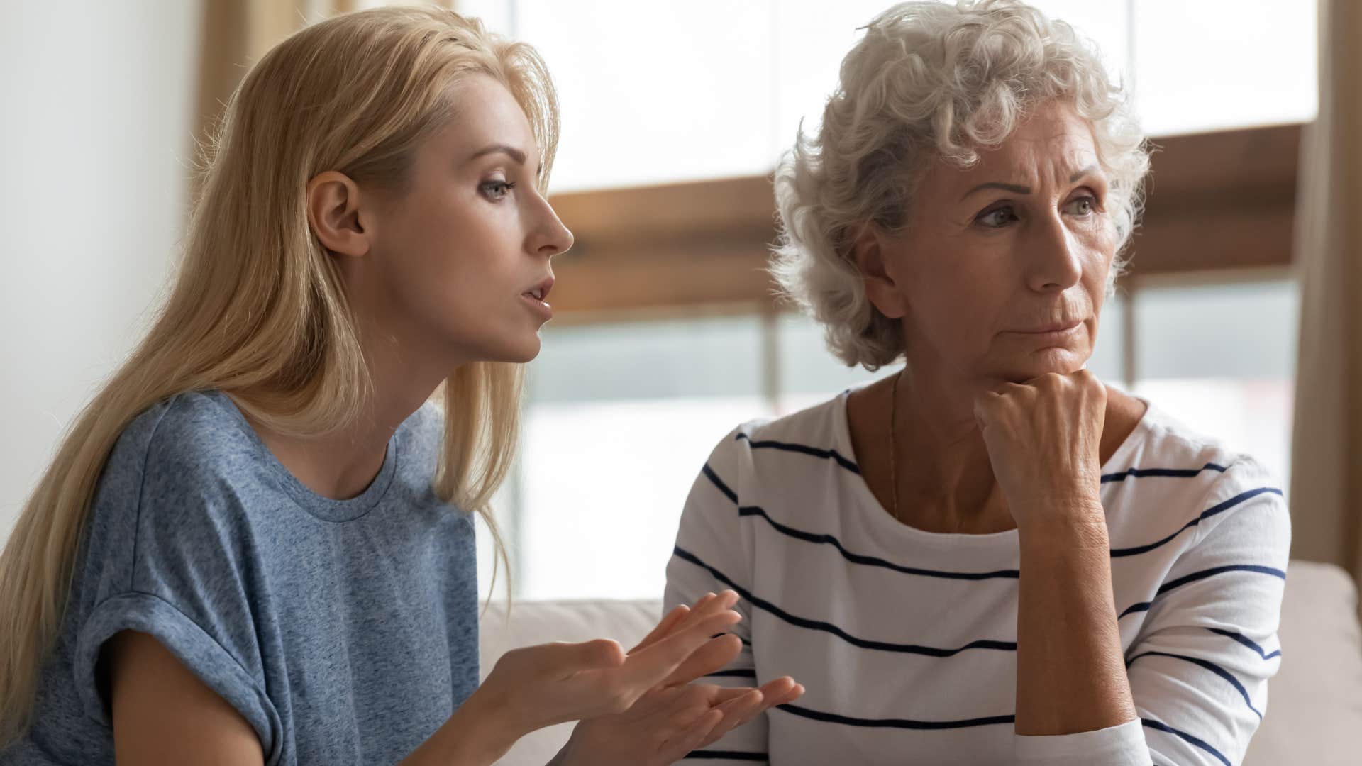 Woman talking to her upset mother at home.