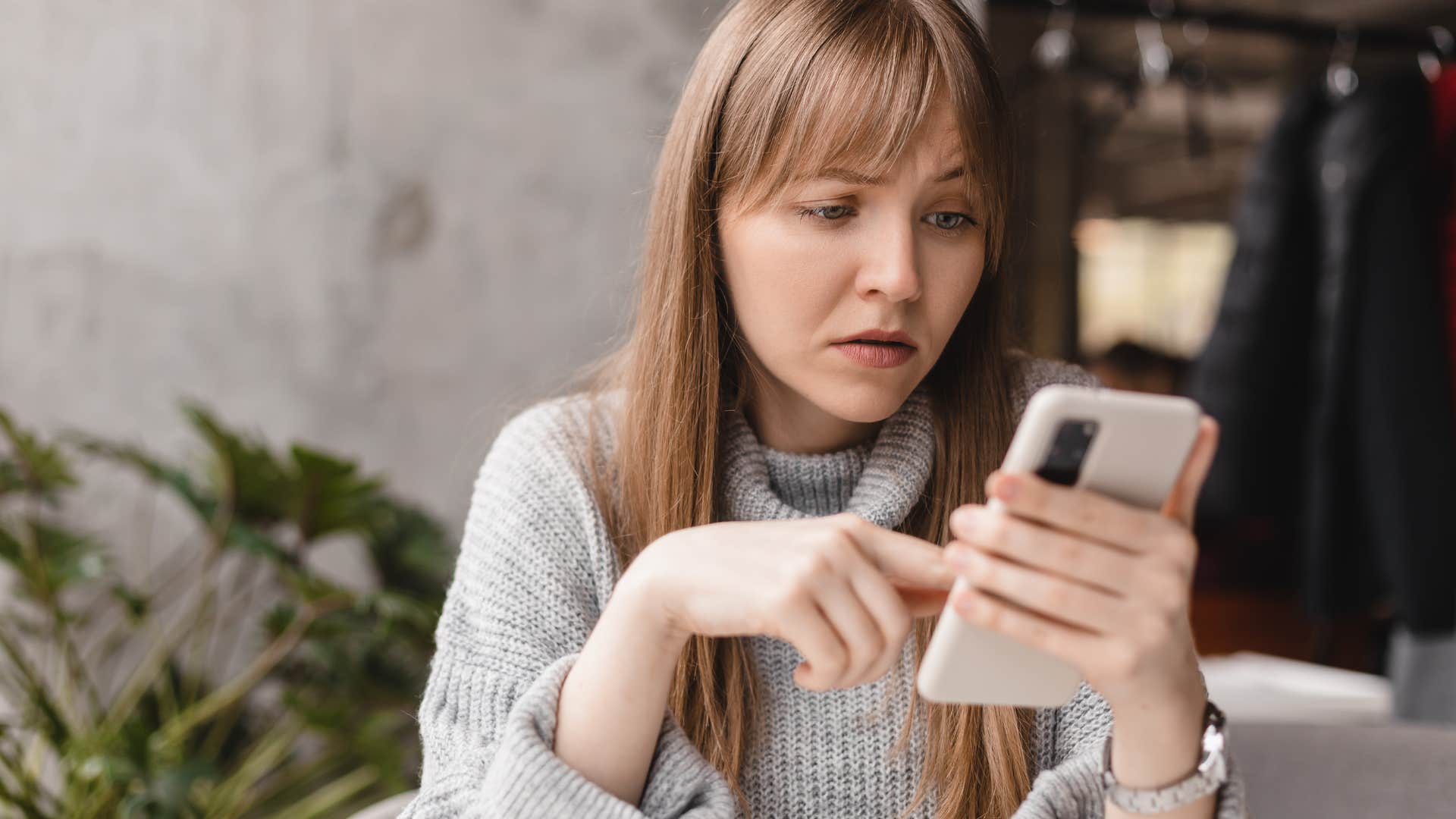 Woman looking annoyed scrolling on her phone.