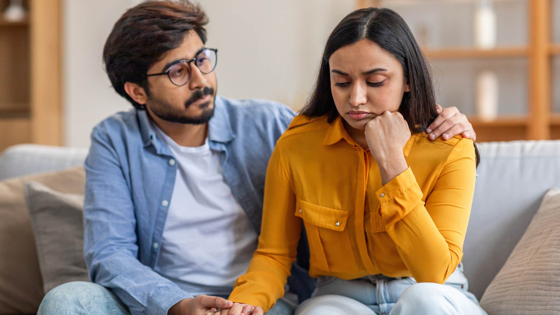 Woman looking sad sitting on a couch with her husband.