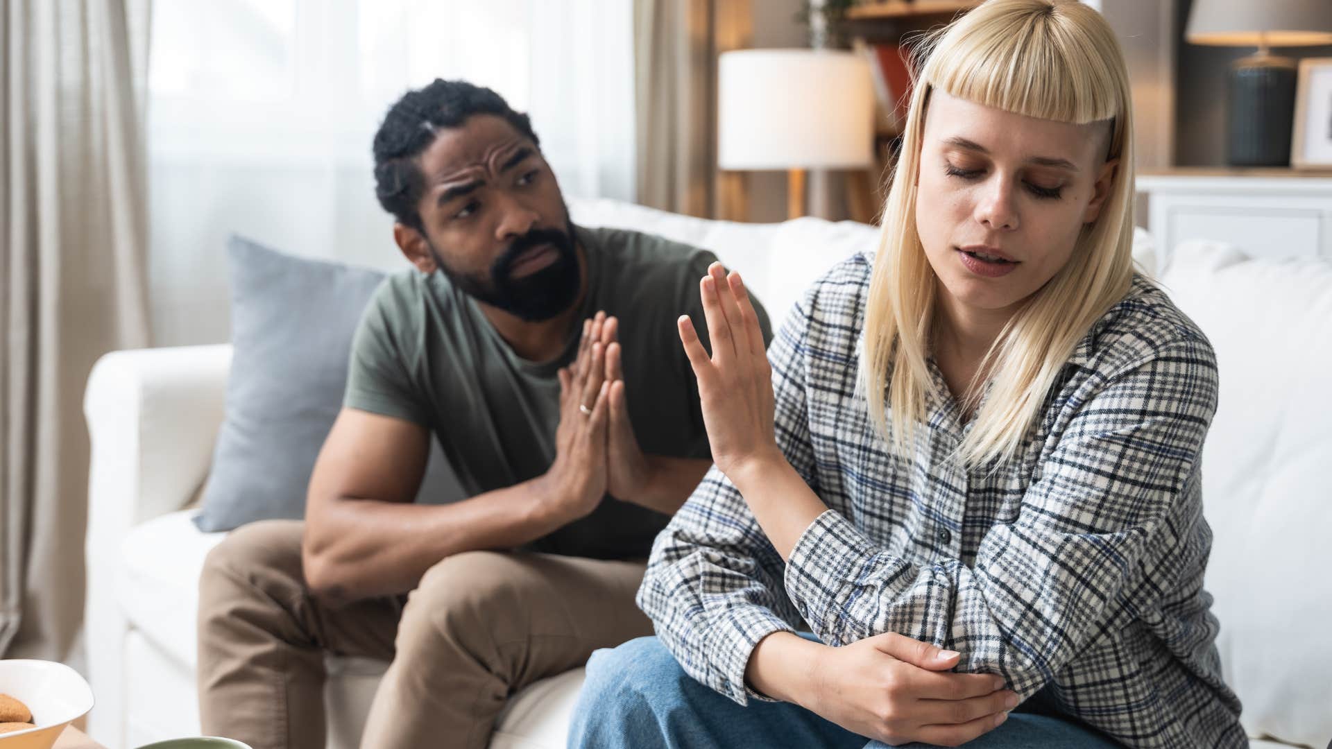 Woman putting her hand up to her boyfriend's face annoyed.