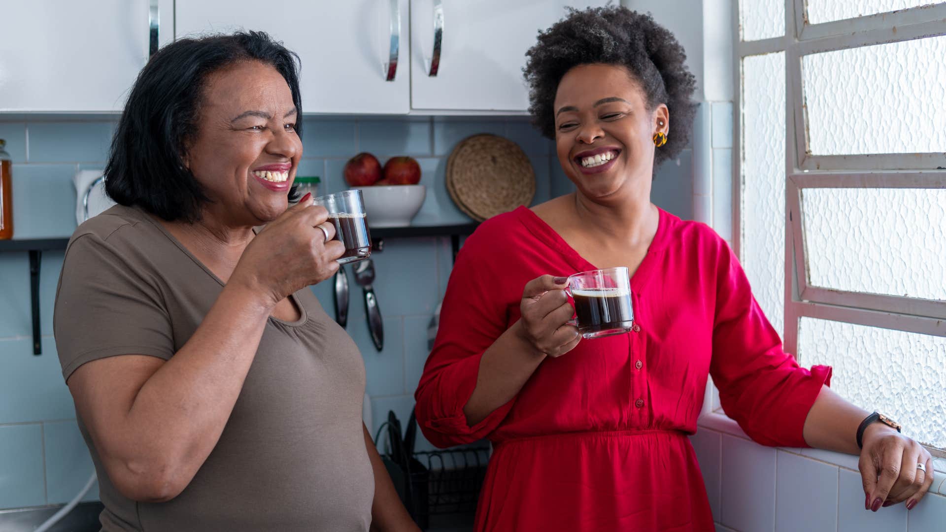 Adult daughter smiling while drinking coffee with her mom