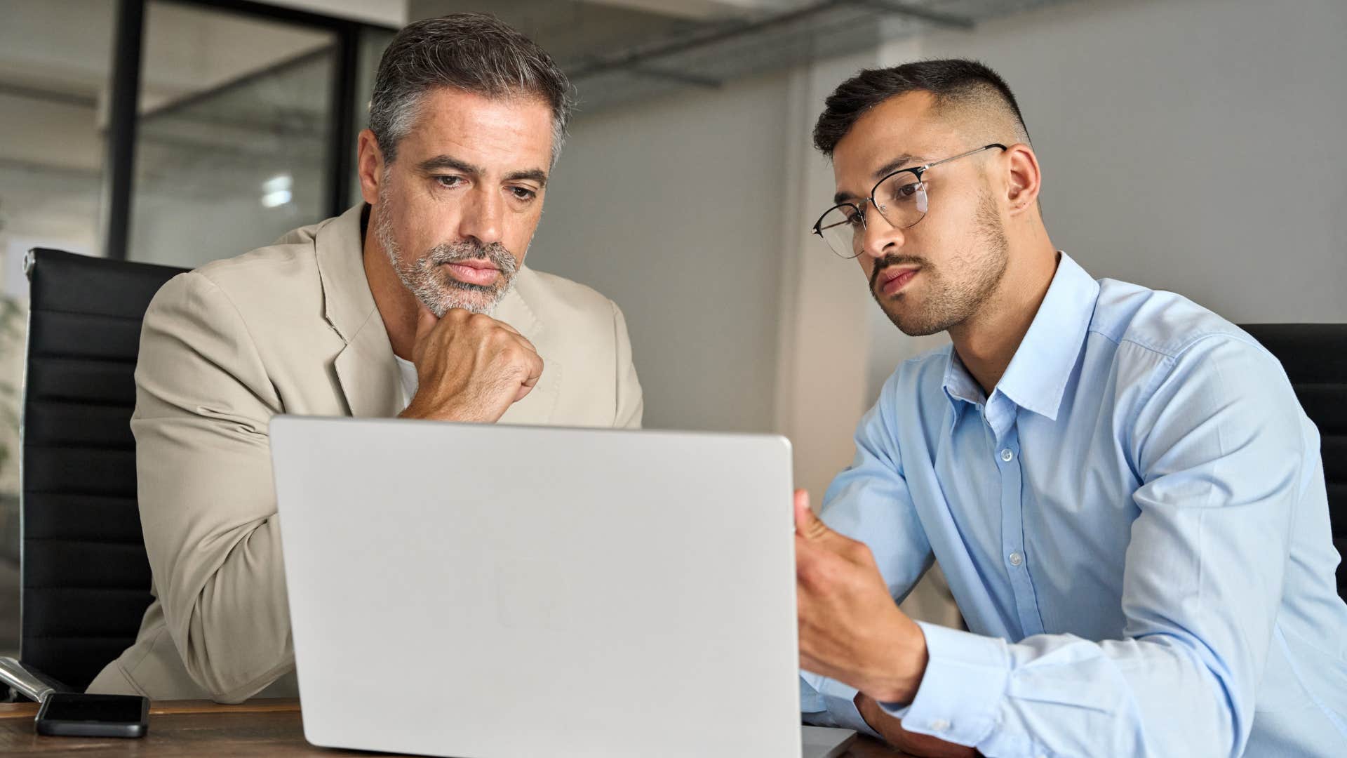 Boss talking to his peer reading from a laptop