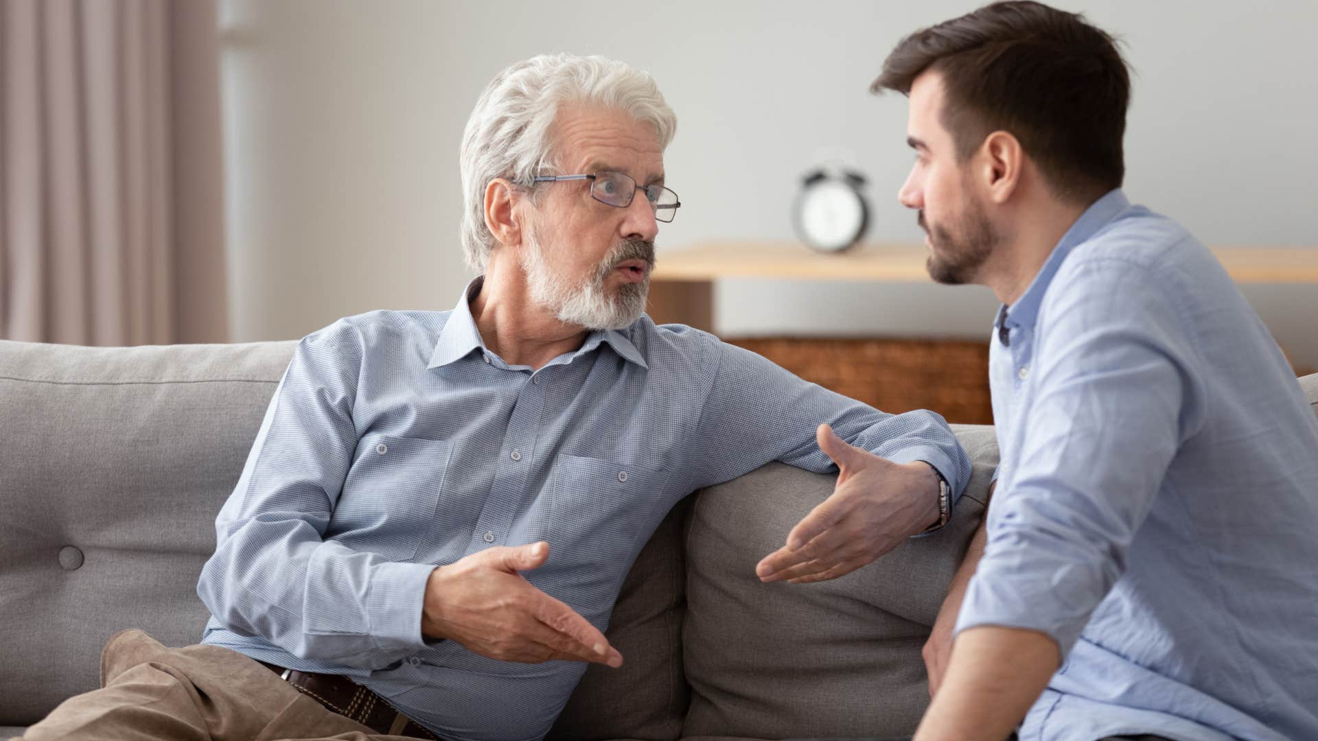 Adult son arguing with his dad on the couch