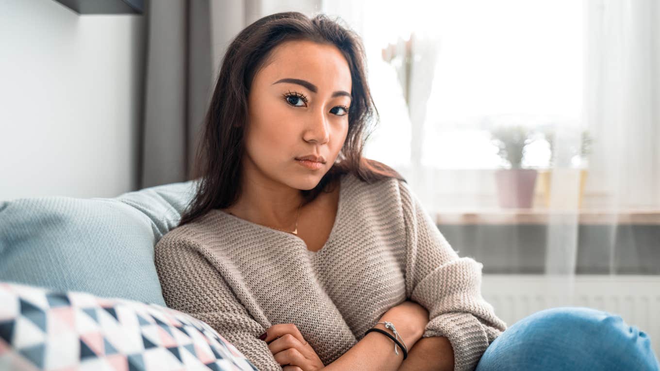 young unsympathetic woman sitting on couch with arms crossed