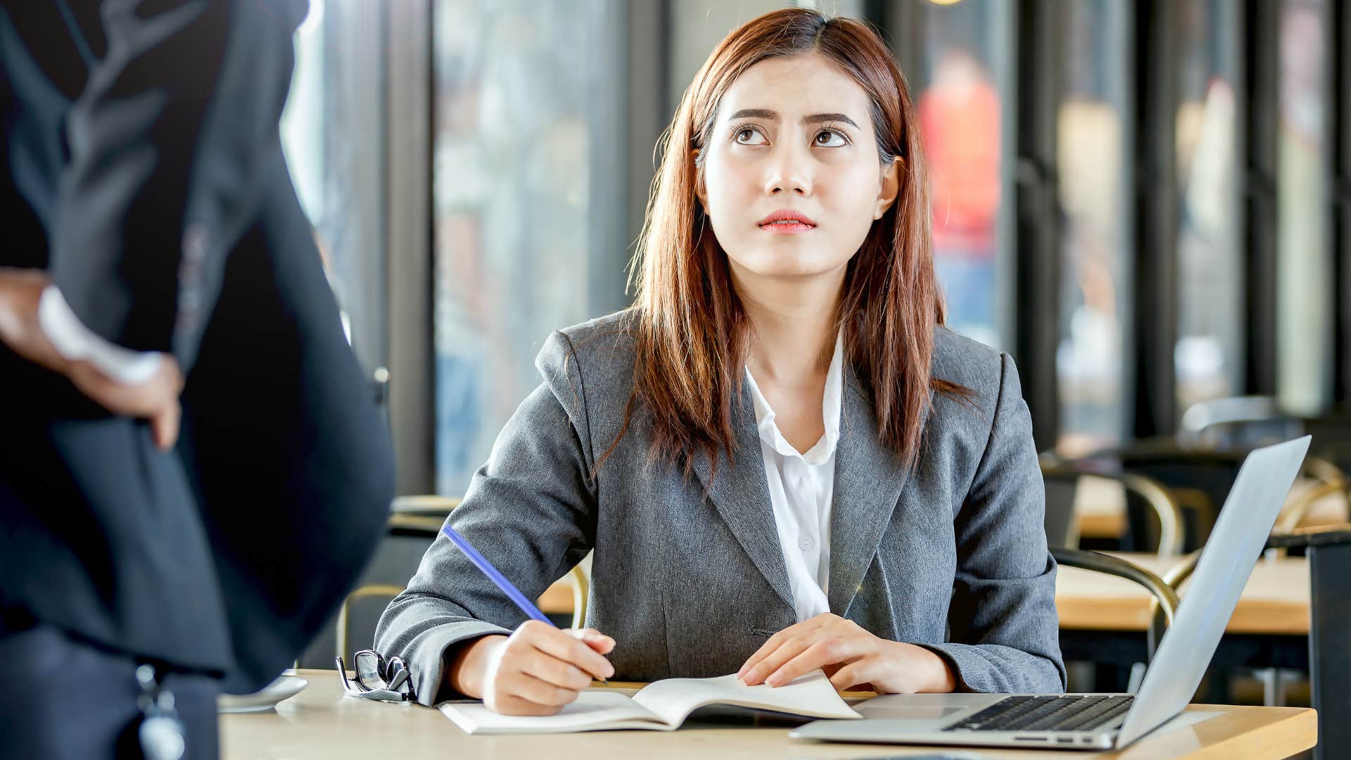 Professional woman looking annoyed talking to her boss.