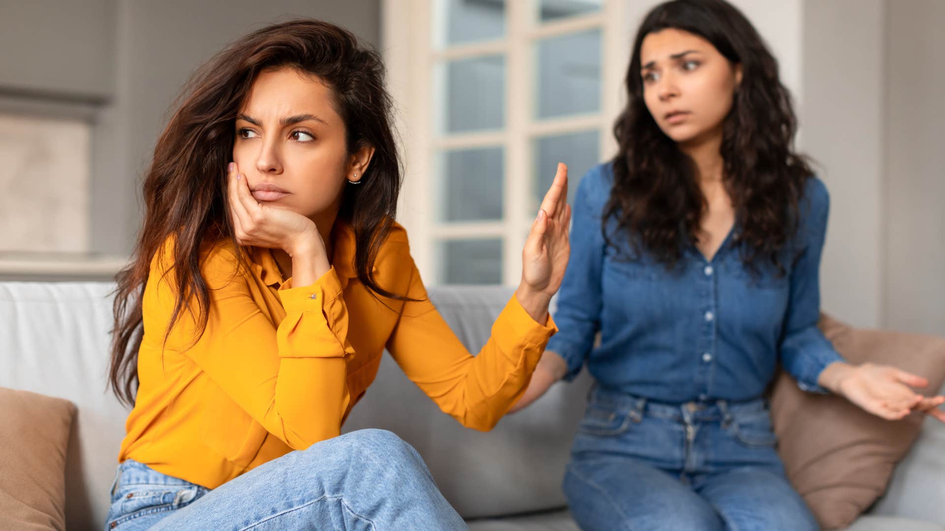 Woman turned away and holding her hand up to a friend.