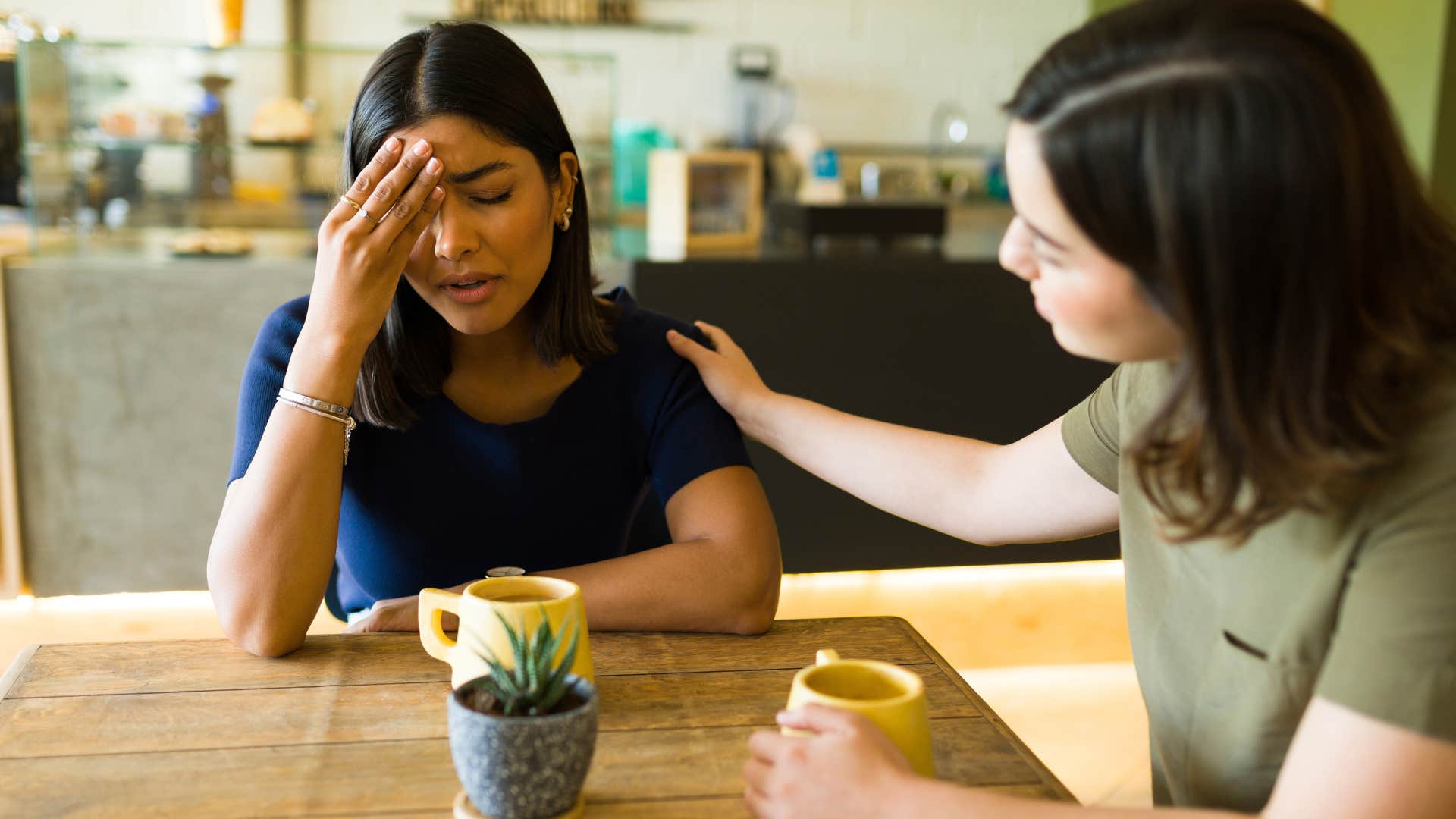 Woman comforting an upset friend at the table.