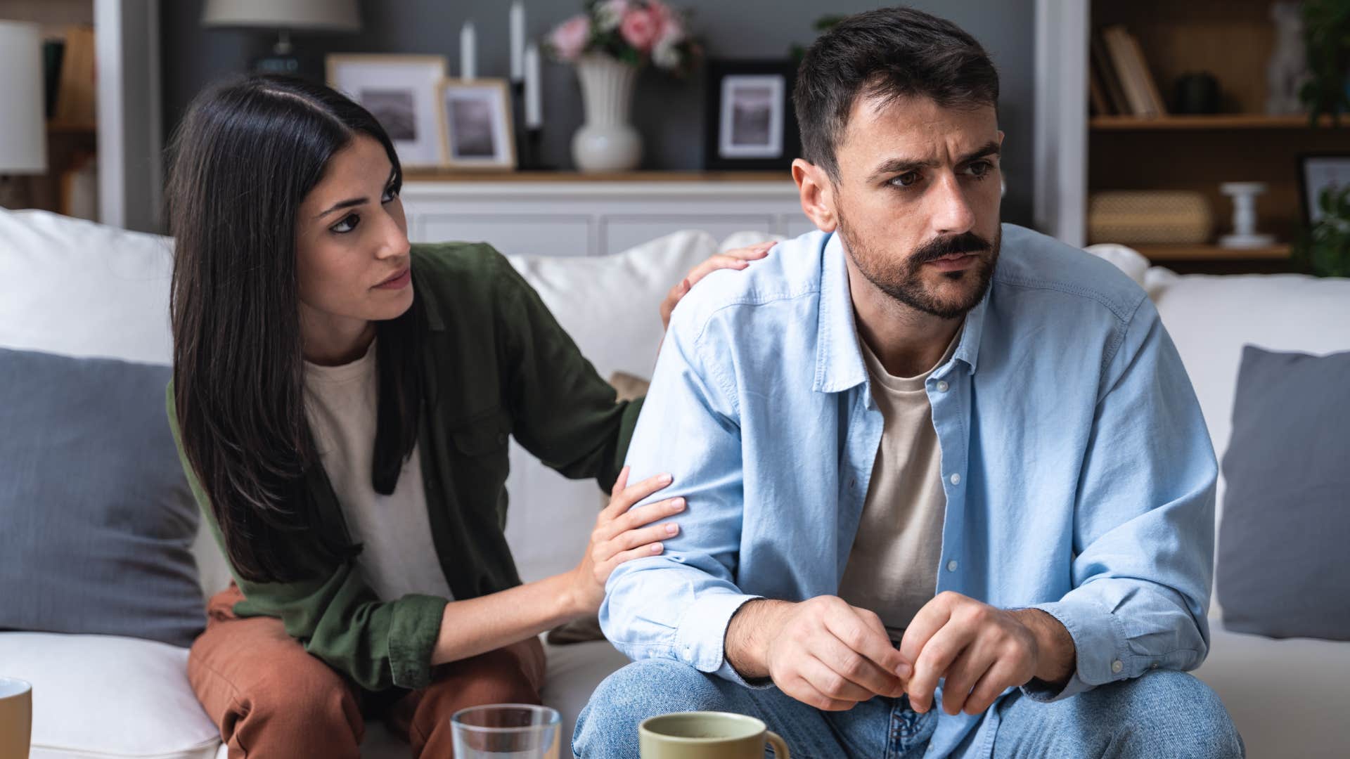 Woman comforting her husband on the couch.