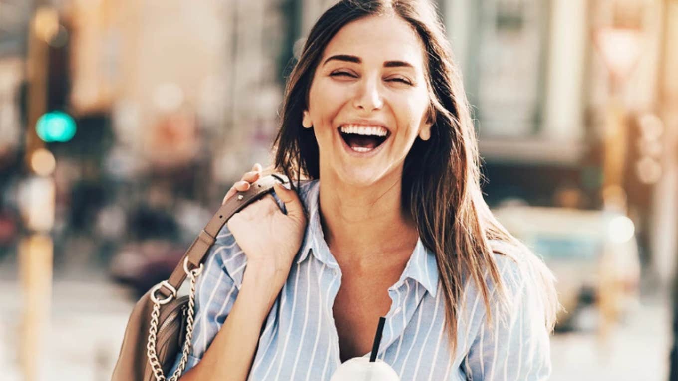 Playful woman smiling and laughing in street. 