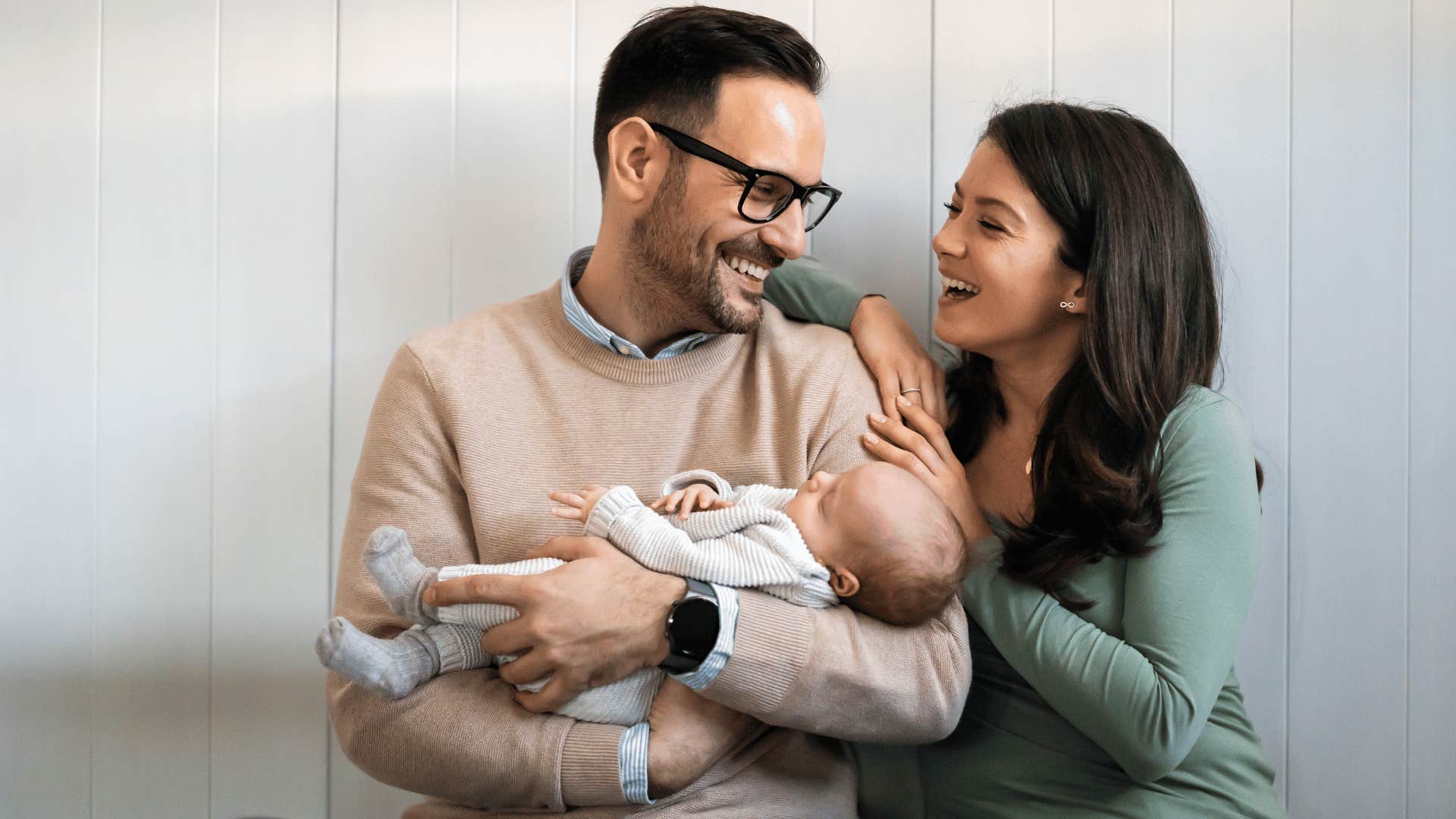 Woman gives positive feedback to confident man holding infant