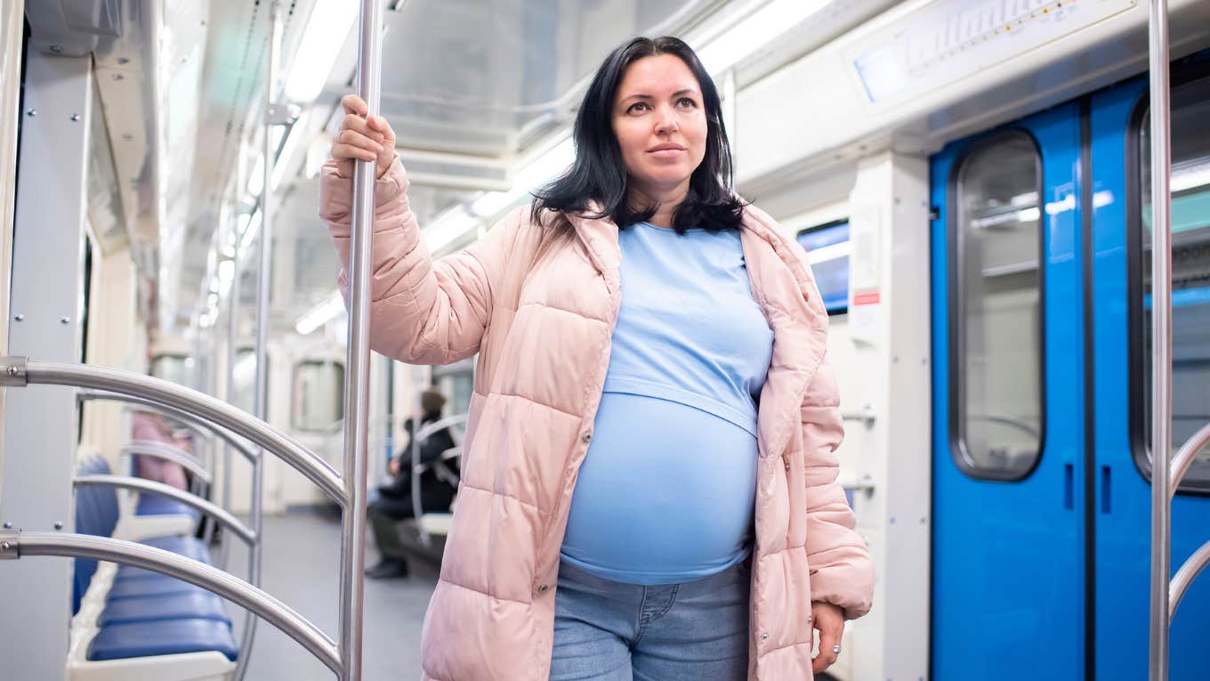 pregnant woman standing on subway