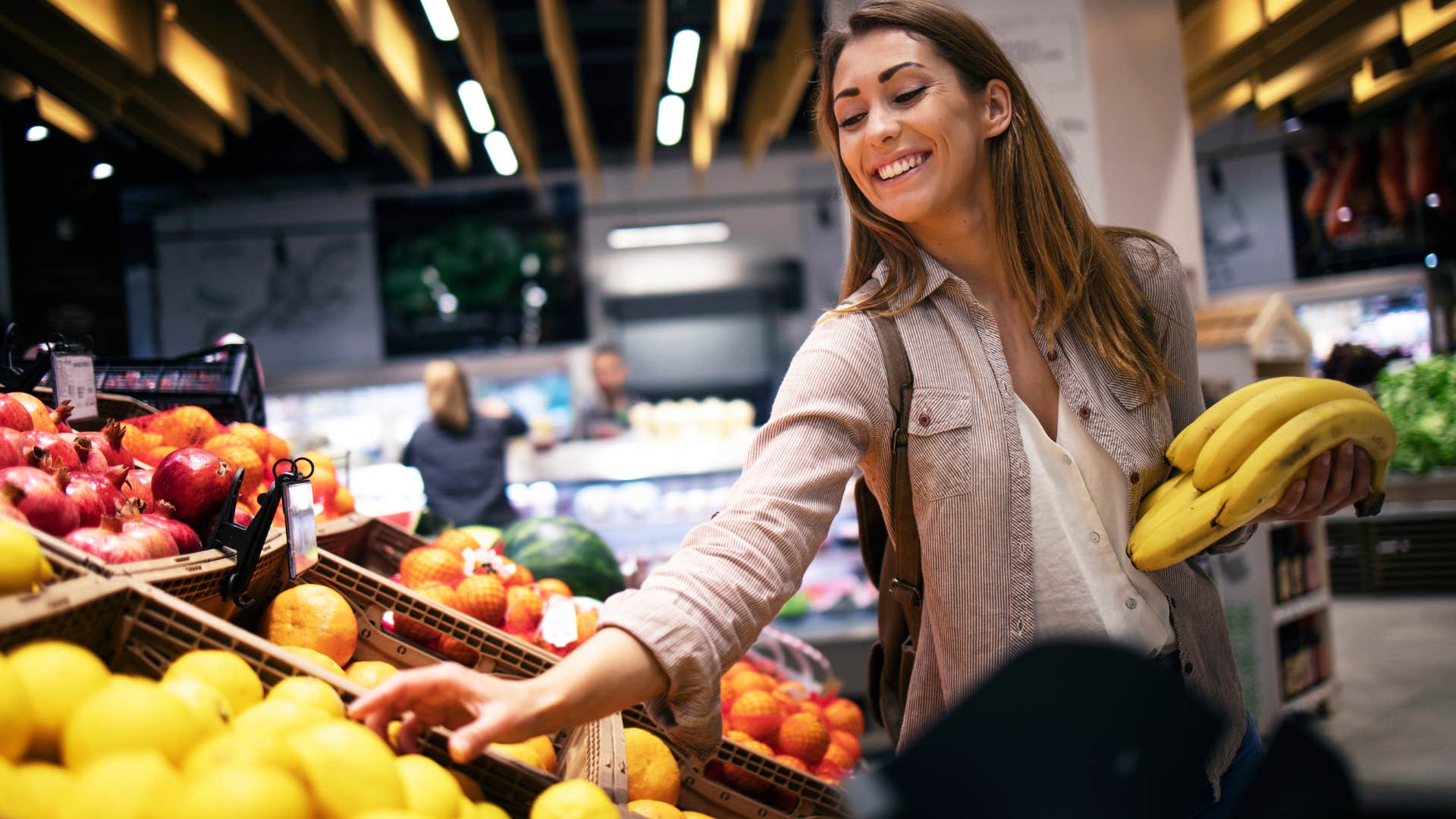 Woman smiling and picking through bananas at the store