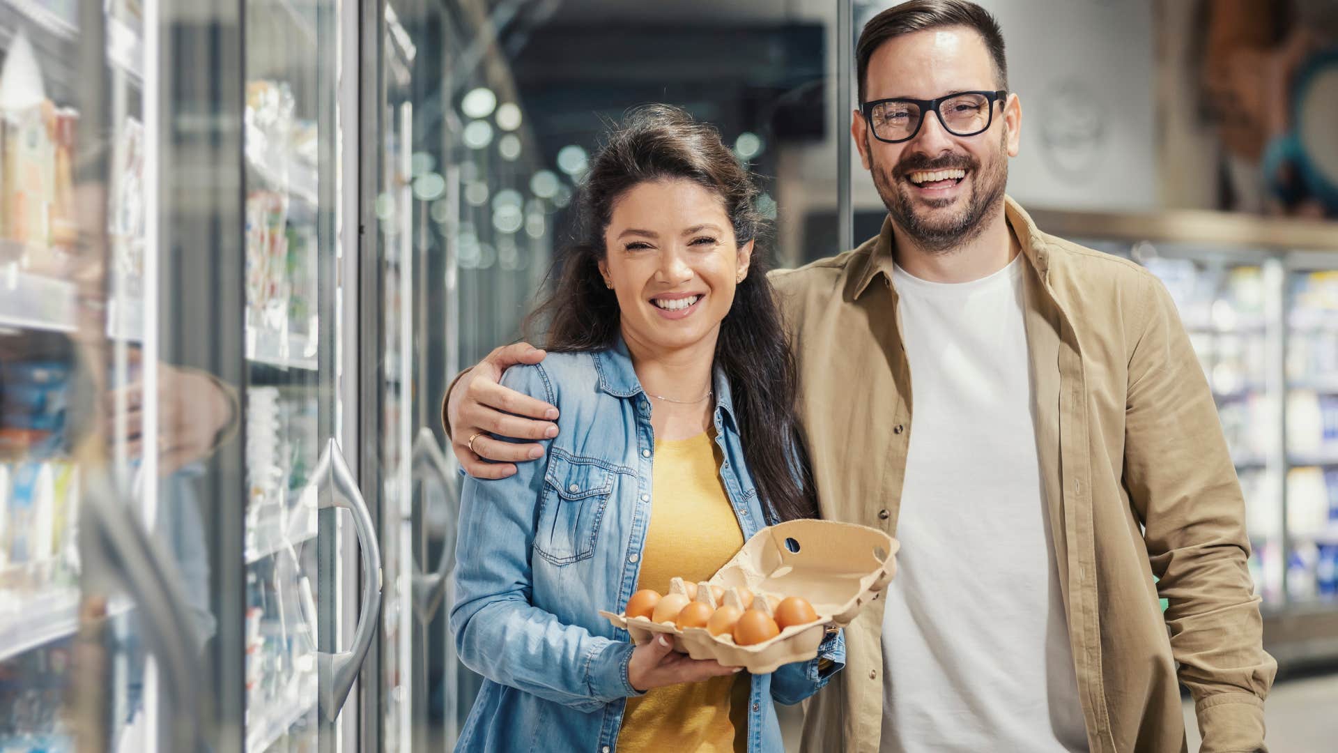 Couple smiling and holding a carton of eggs in the grocery store