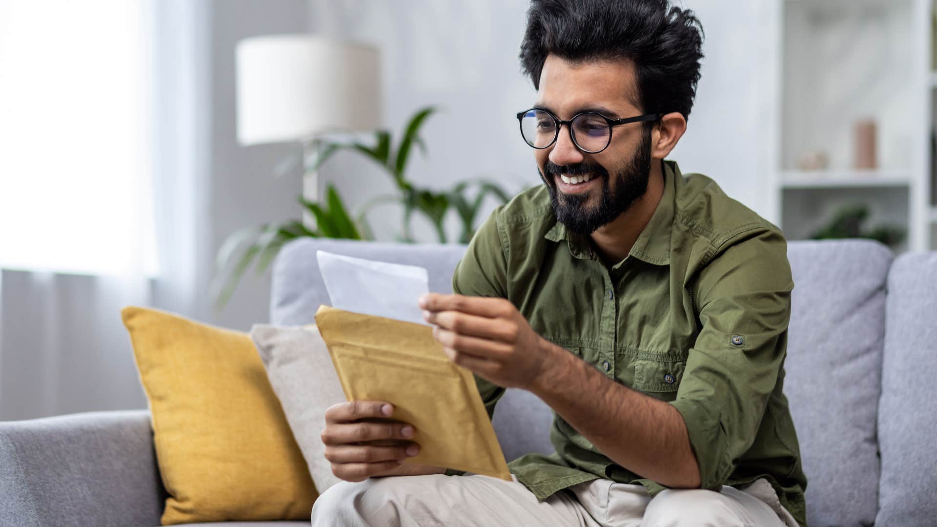 Man smiling while putting a letter into an envelope.