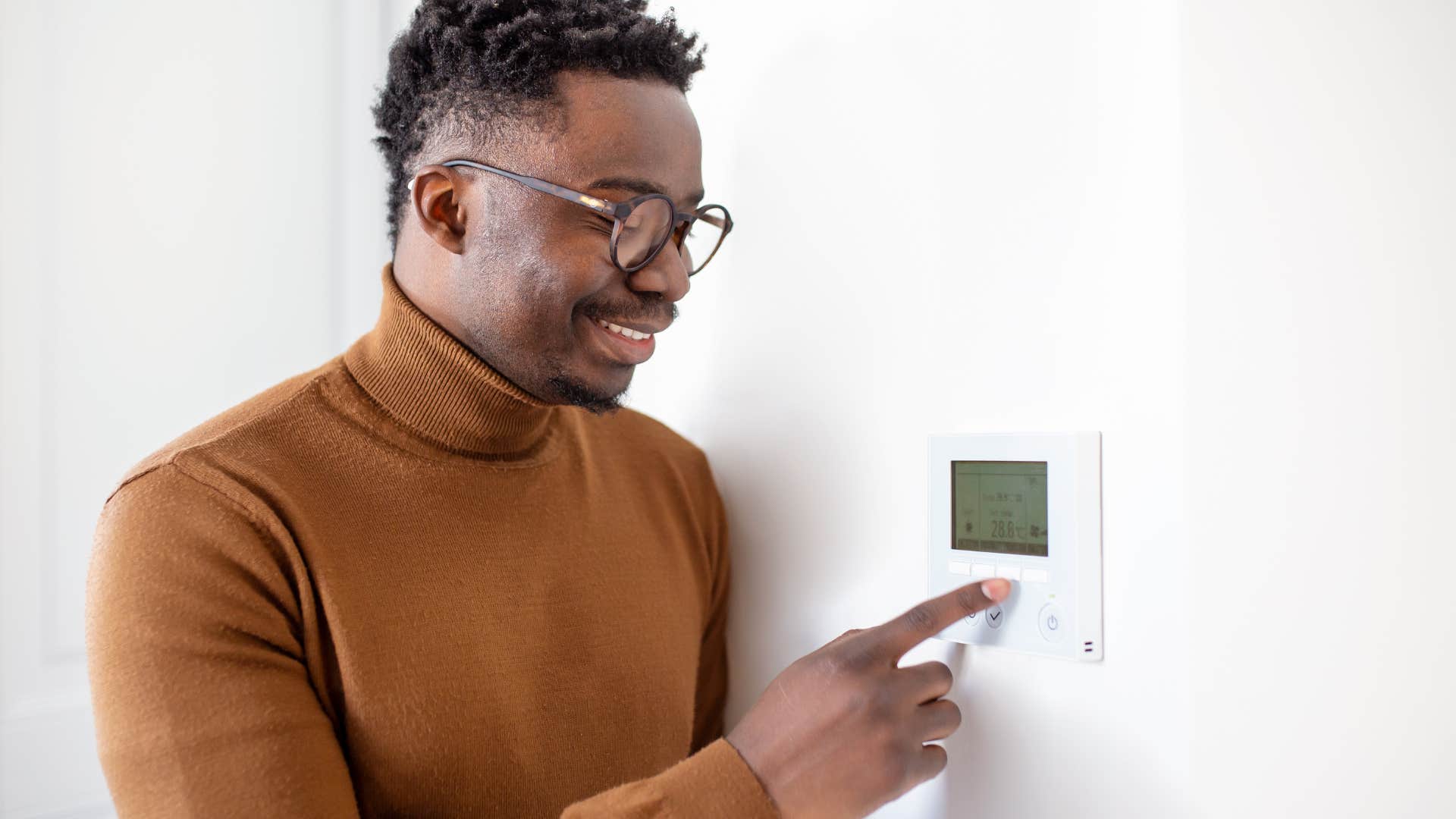 Man changing the thermostat in his house. 